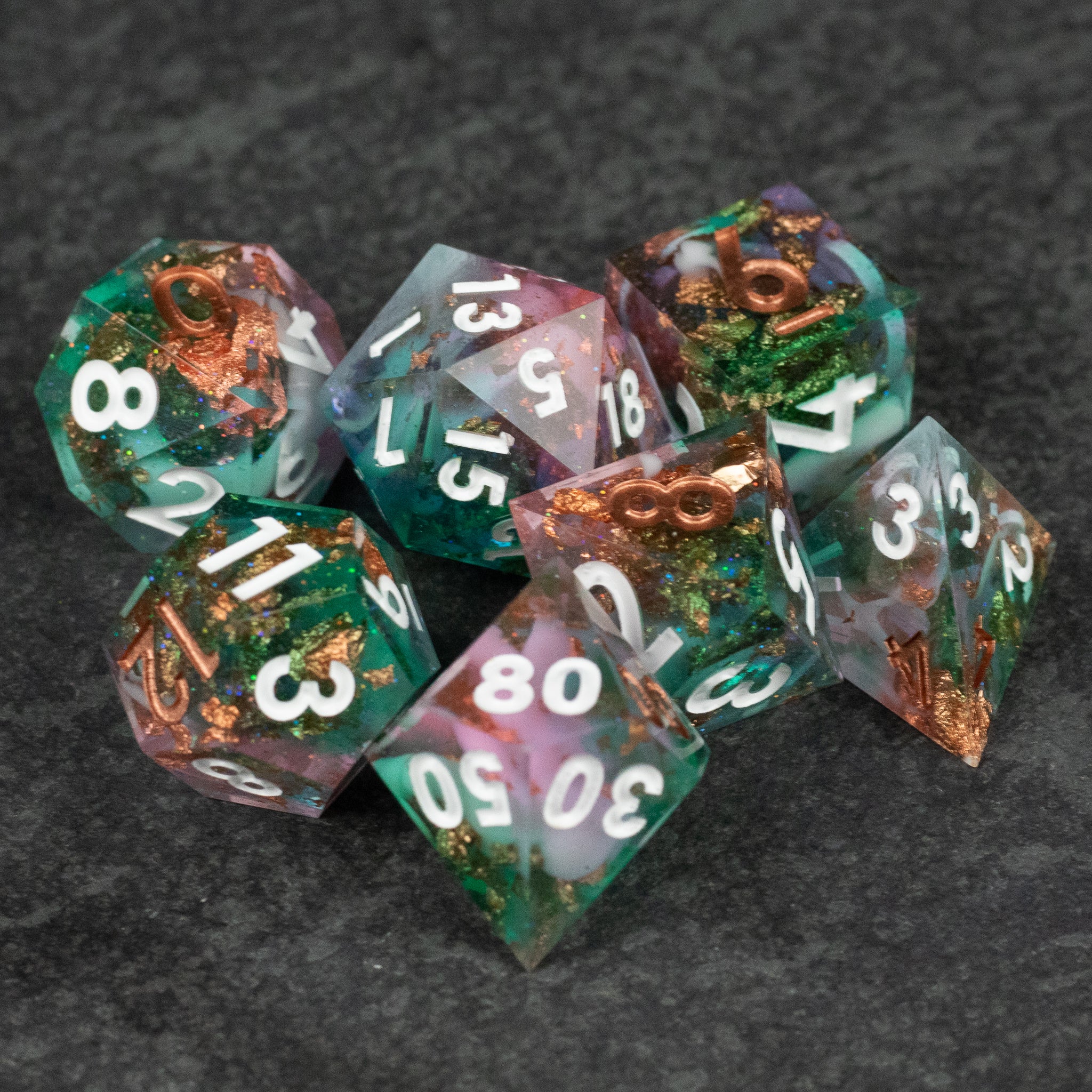Scapeshift Dice Set - Set of translucent sharp-edged polyhedral dice with swirling green, purple, and copper inclusions, white numbering.