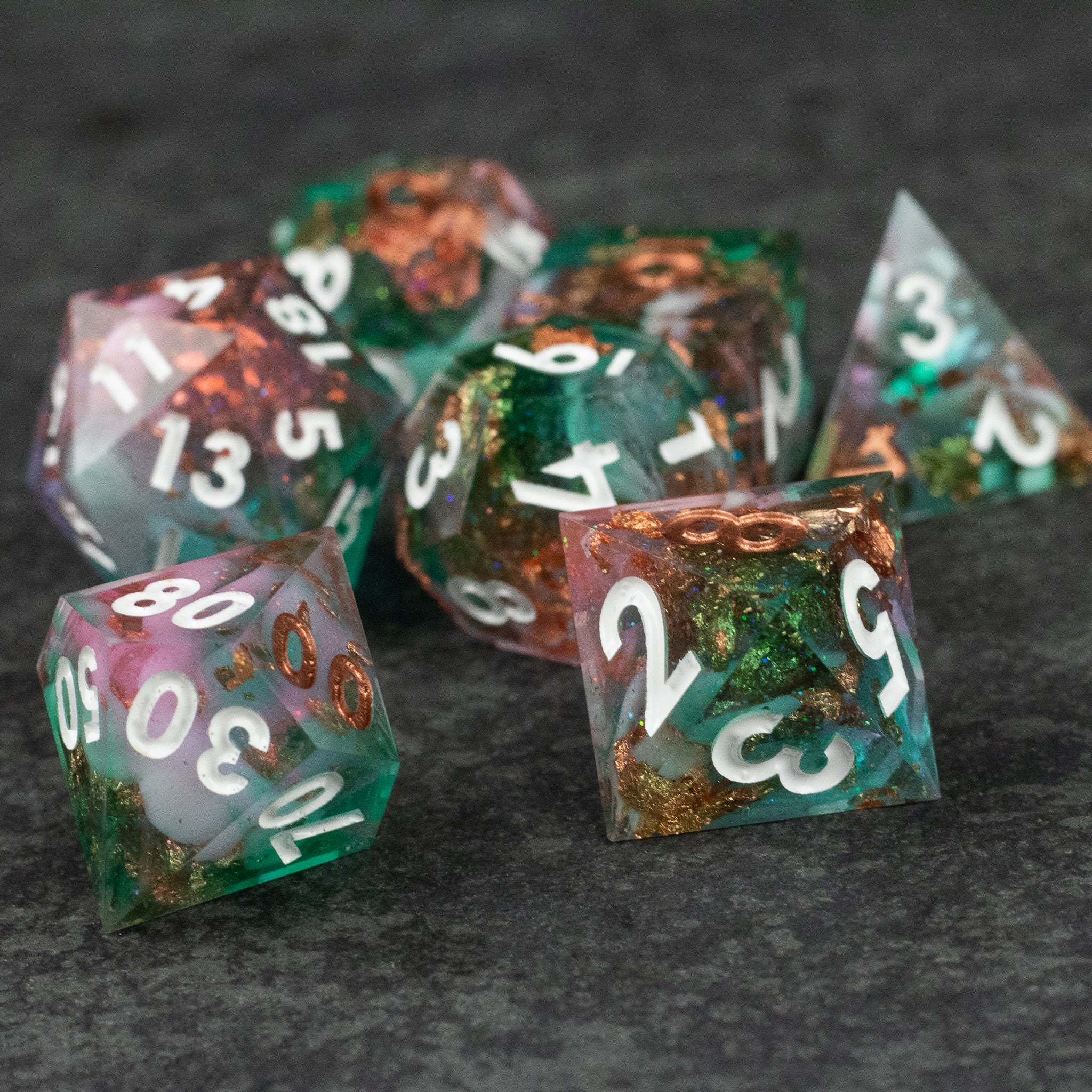 Scapeshift Dice Set - Seven polyhedral dice with sharp edges, translucent green and orange mix, white numbering.