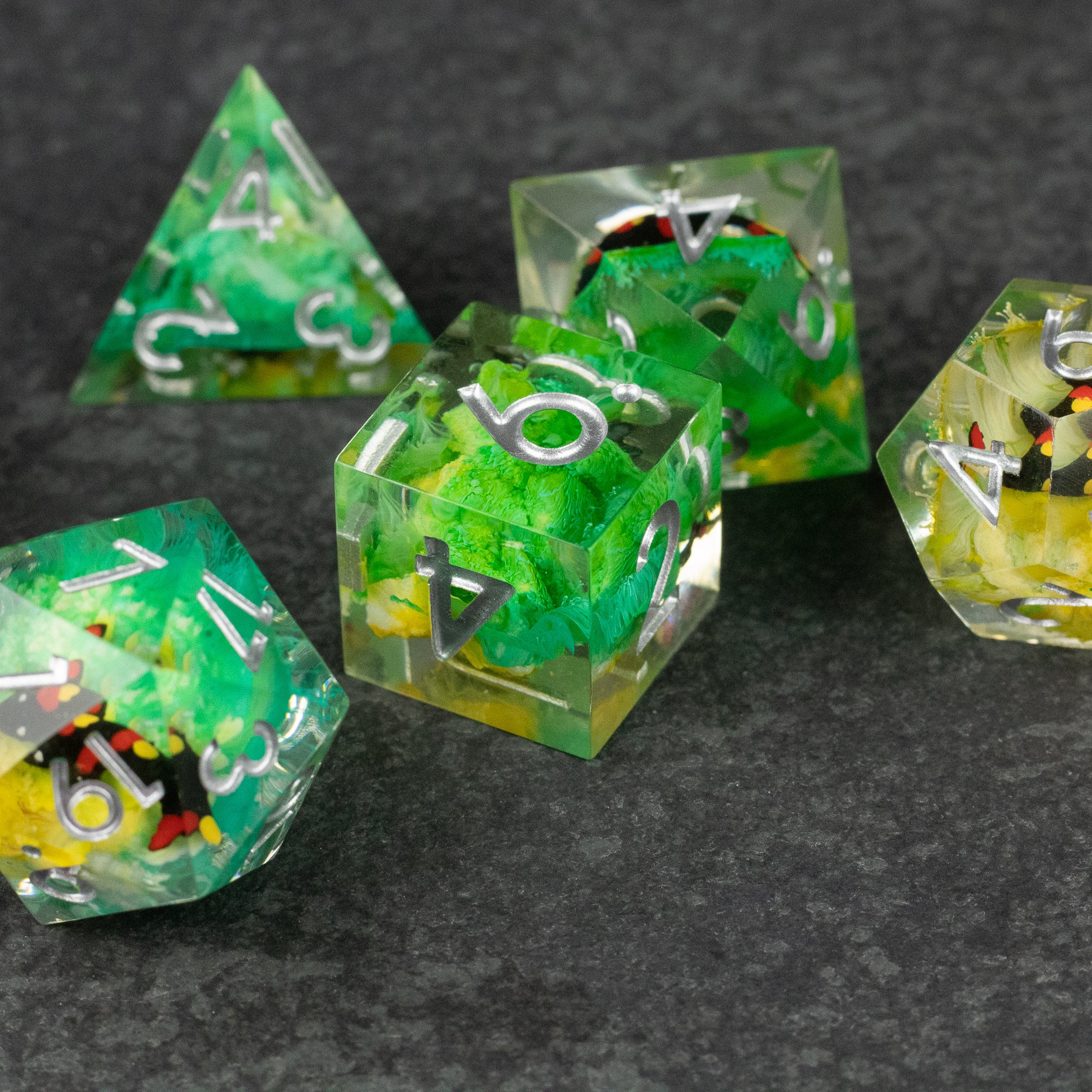 Green Lagoon Dice Set - Set of sharp-edged polyhedral dice with translucent green and clear resin, embedded colorful flakes, and white numbering.