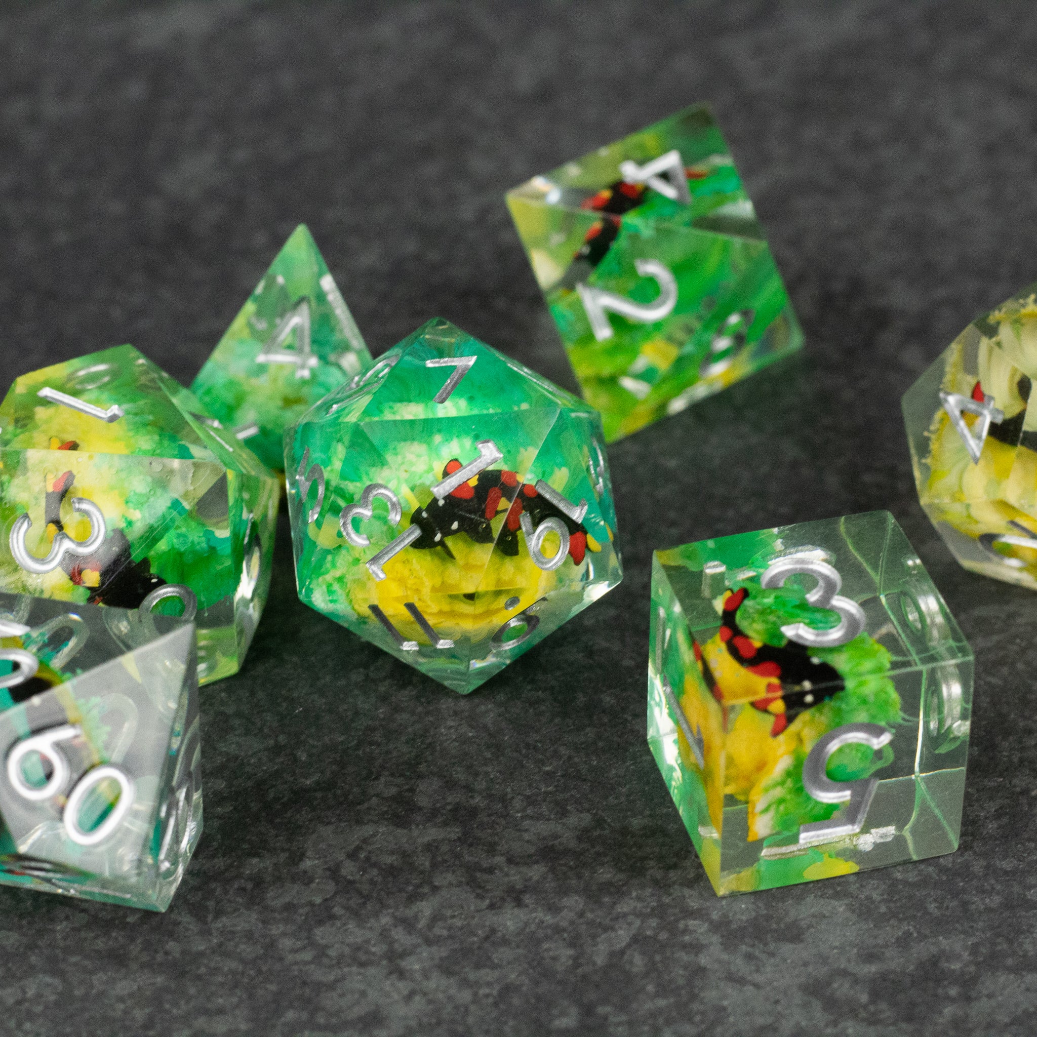 Green Lagoon Dice Set - Transparent green polyhedral dice set with colorful insect inclusions and white numbering.