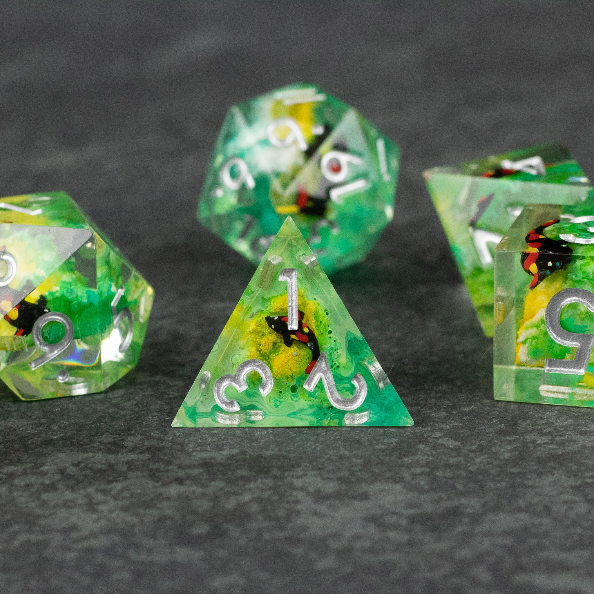 Green Lagoon Dice Set - Set of six translucent green polyhedral dice with embedded yellow and black inclusions, white numbering, and sharp edges on.