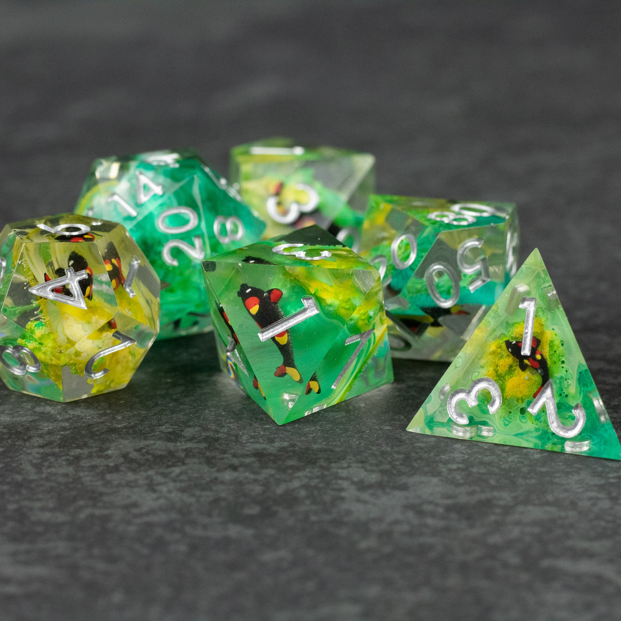 Green Lagoon Dice Set - Translucent green and yellow sharp-edged polyhedral dice set with white numbers and black spotted inclusions.