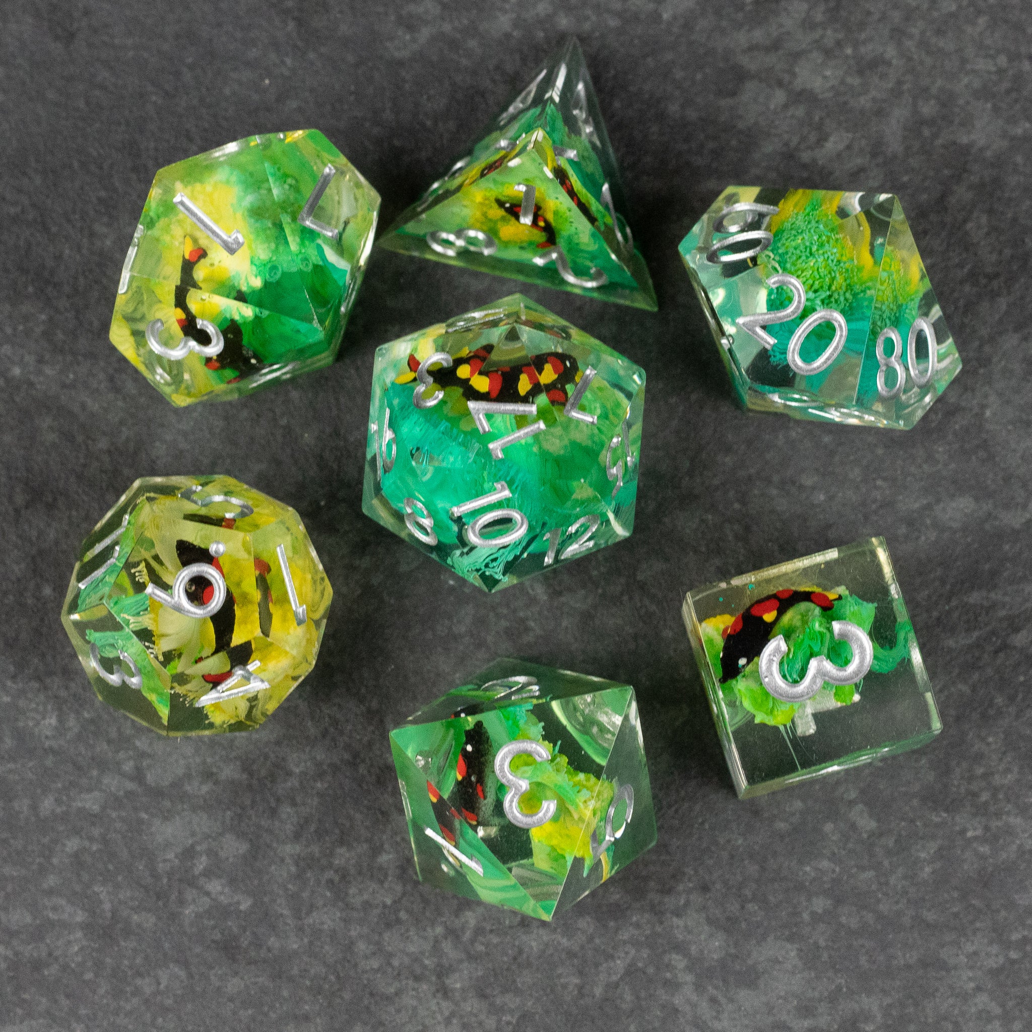 Green Lagoon Dice Set - Green translucent seven-piece dice set with sharp edges, swirling yellow and black inclusions, and white numbering.
