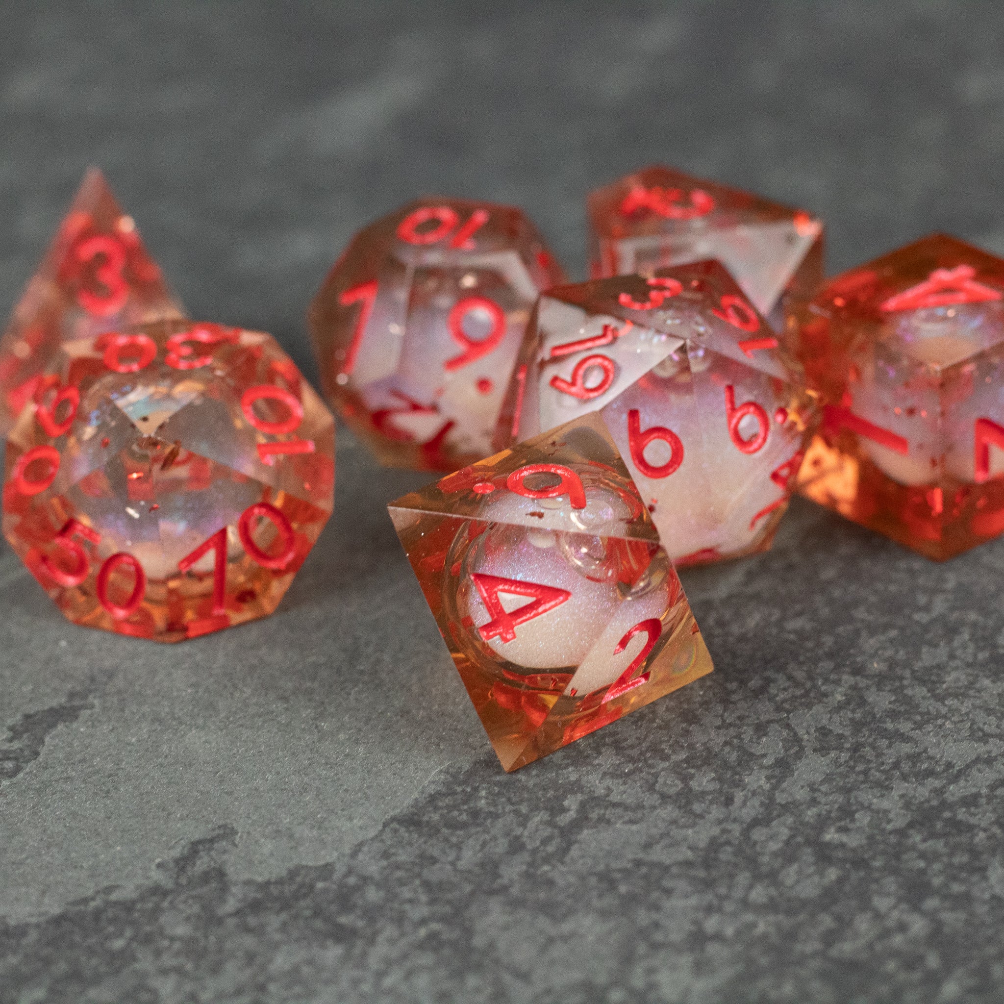 Potion of Fire Breath - Liquid Core Dice Set - Set of translucent red and clear sharp-edged polyhedral dice with fiery liquid core and red numbers.