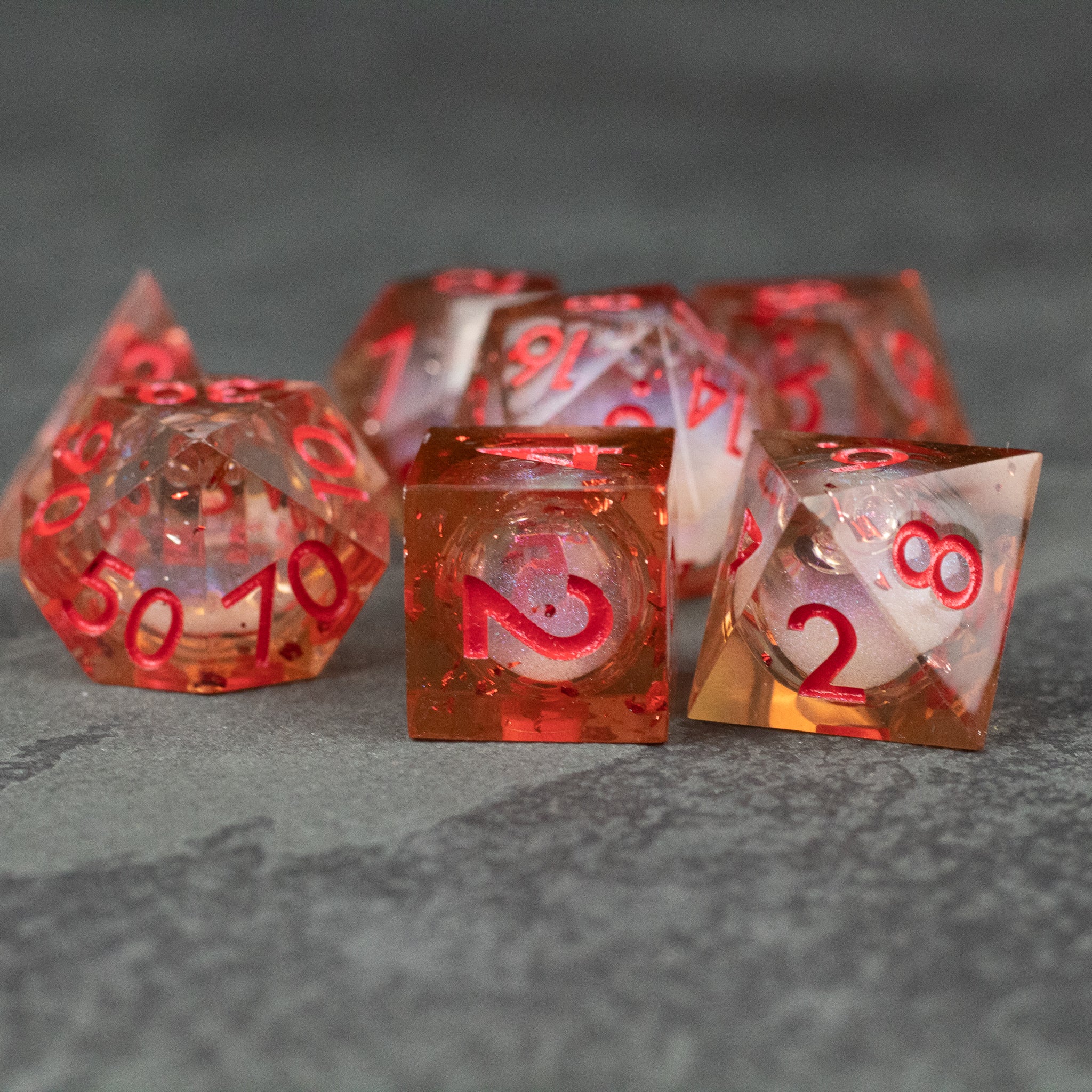 Potion of Fire Breath - Liquid Core Dice Set - Set of six transparent resin dice with swirling red liquid core and sharp edges, featuring red numbers.