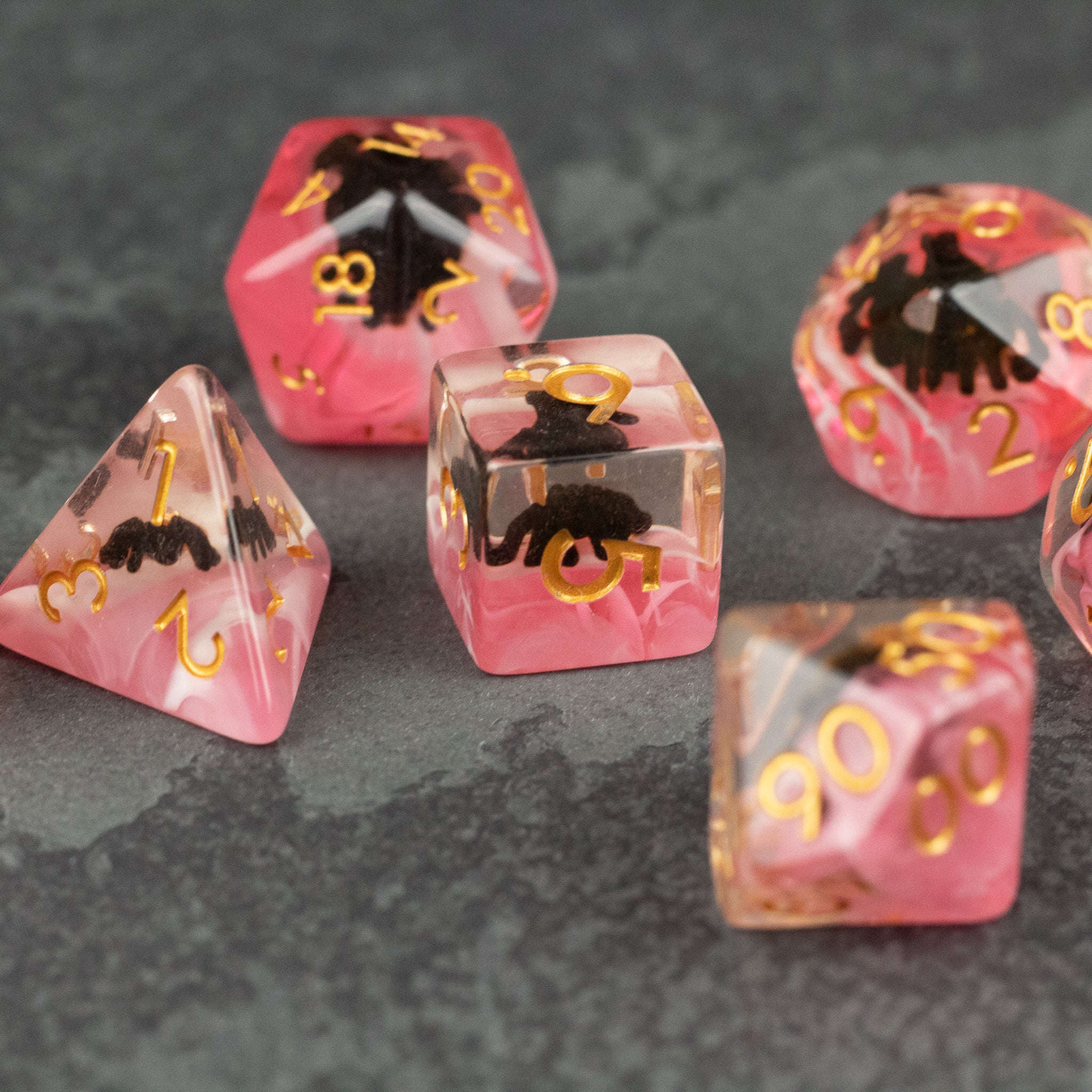 Black Spider Dice Set - Red - Red translucent polyhedral dice set with black spider inclusions and gold numbers, six pieces.