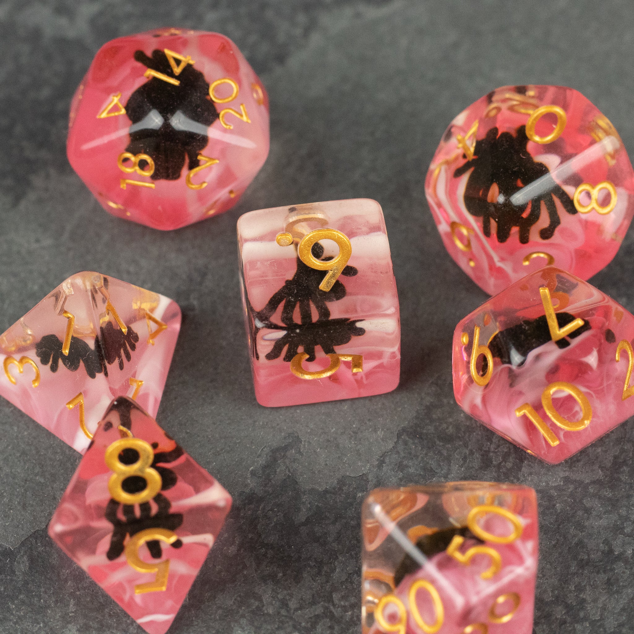 Black Spider Dice Set - Red - Red translucent polyhedral dice set with black spider silhouettes and gold numbers.