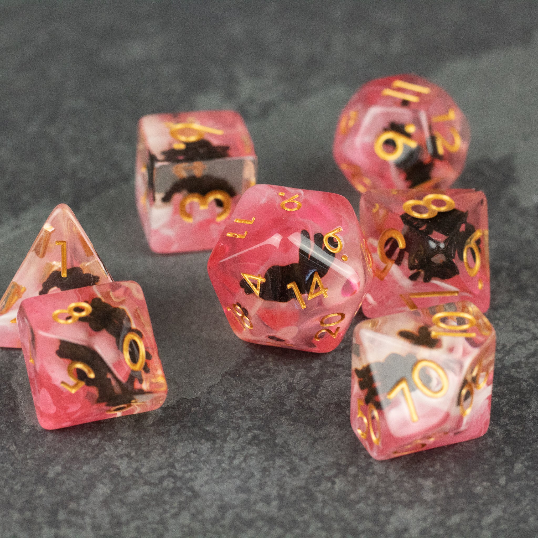 Black Spider Dice Set - Red - Set of six translucent red polyhedral dice with black spider designs and gold numbers on a dark surface.