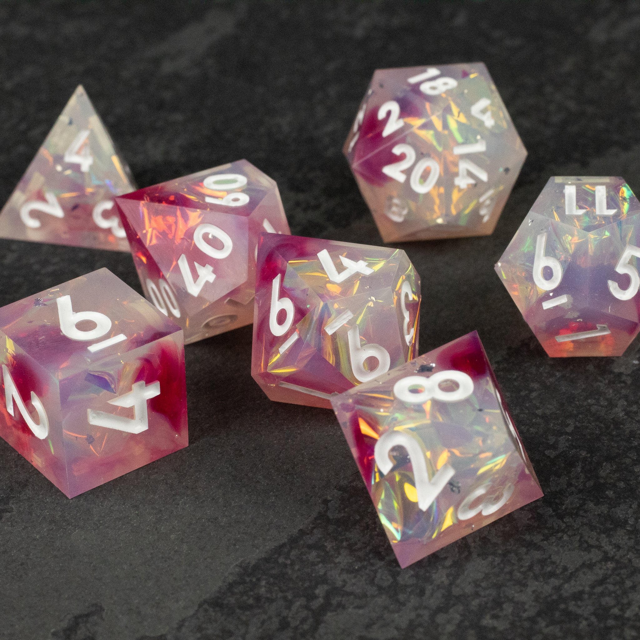 Lover's Kiss Dice Set - Seven translucent polyhedral dice in pink and clear swirls with sharp edges and white numbers.