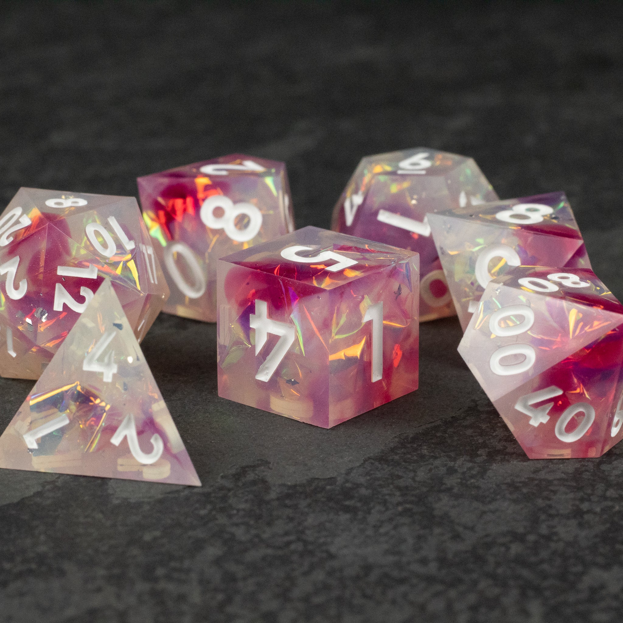 Lover's Kiss Dice Set - Translucent pink and white sharp-edged polyhedral dice set with gold numbers, including d4, d6, d8, d10, d12, and d20 shapes.