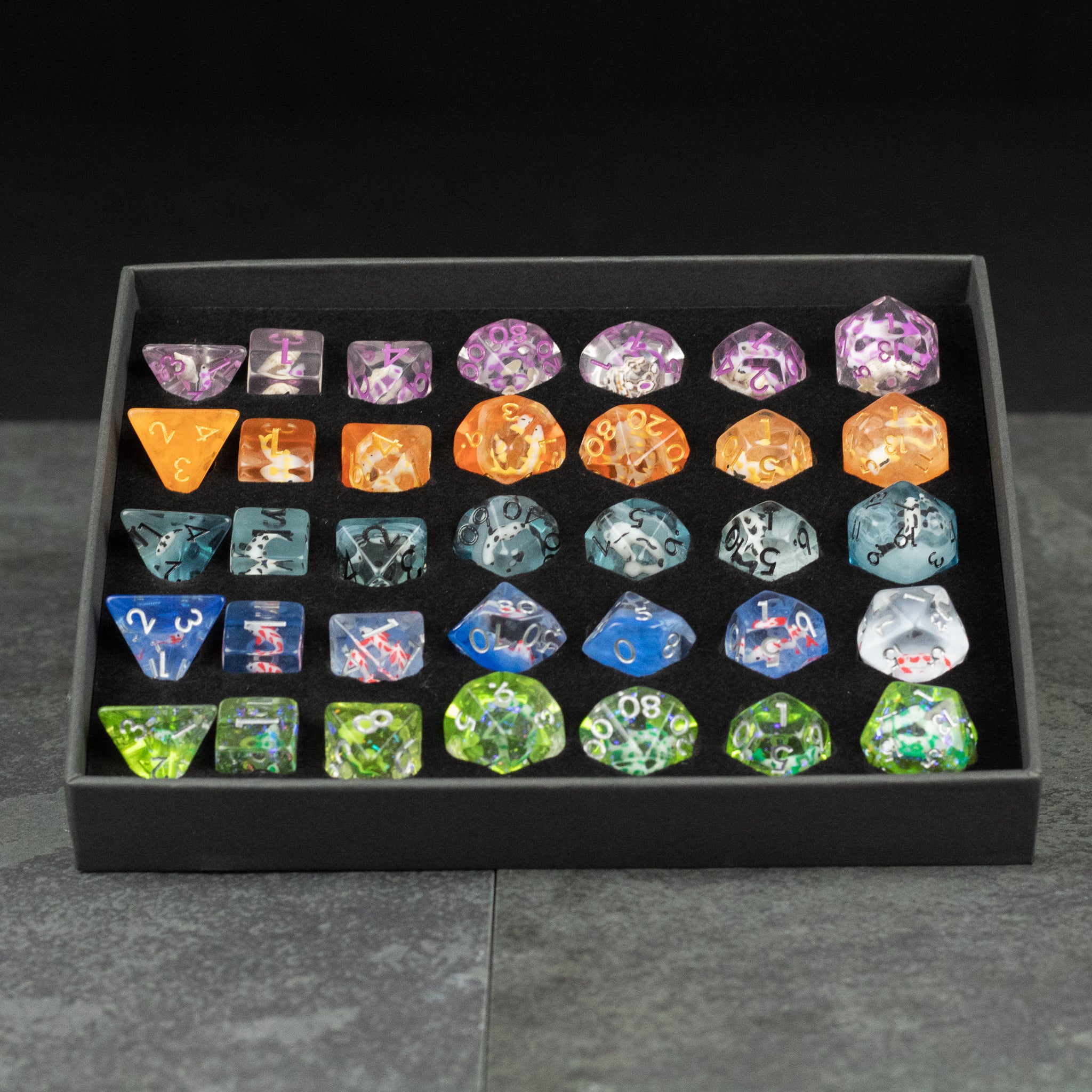 Koi Fish Dice Set Gift Box - Colorful koi fish-themed polyhedral dice set with orange, blue, purple, and green designs in a black gift box.