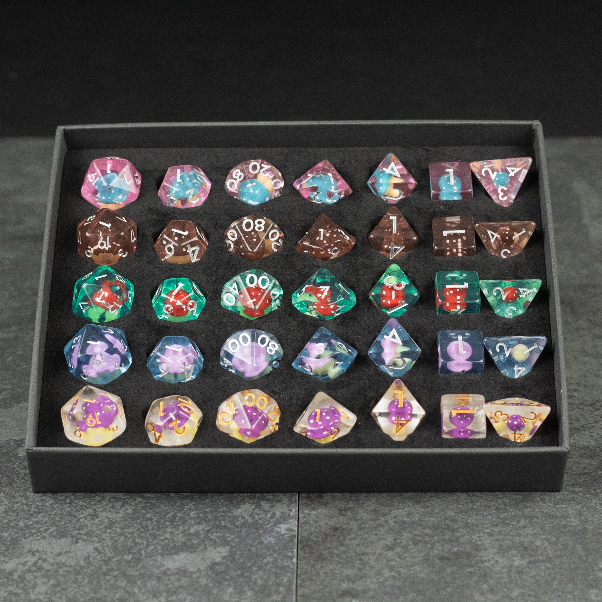 Mushroom Dice Set Gift Box - Colorful mushroom-themed polyhedral dice set with white numbers, arranged in black gift box compartments.
