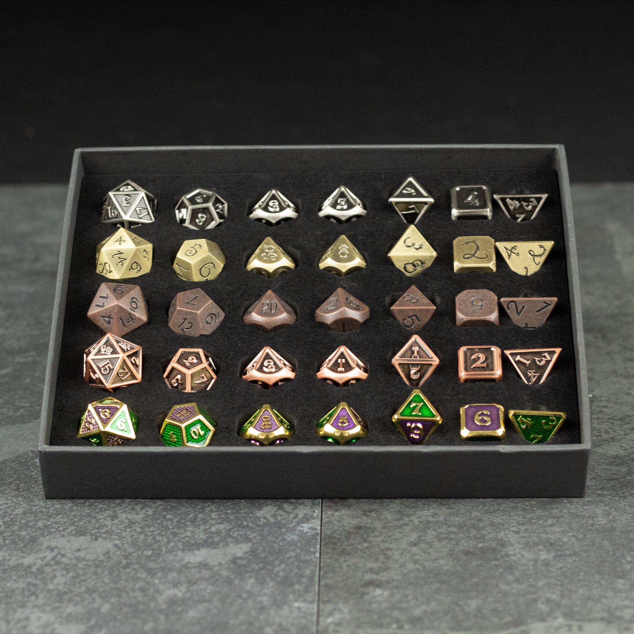 Metal Dice Set Gift Box - Set of 36 metal polyhedral dice in silver, gold, bronze, and green with intricate designs in a black display box.