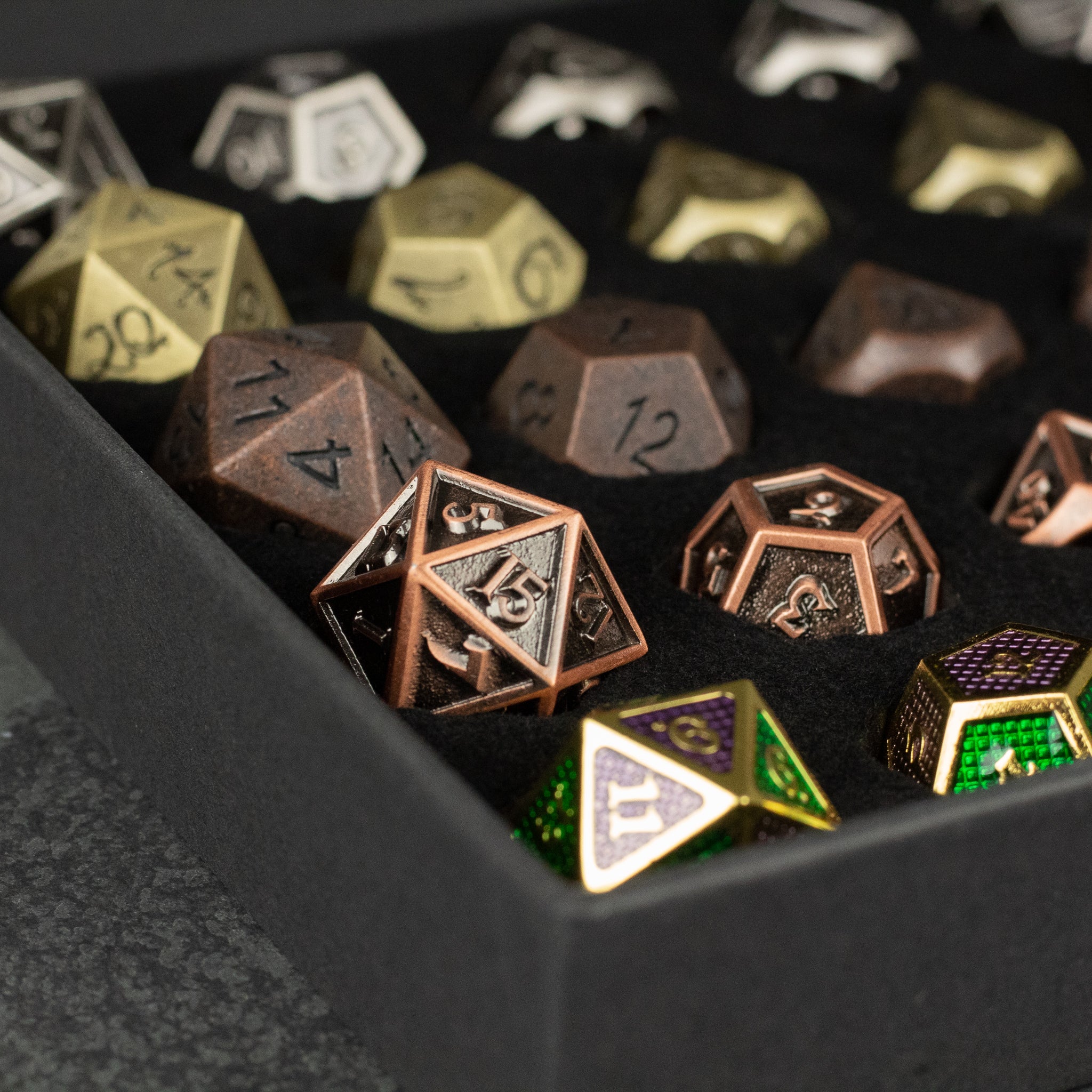 Metal Dice Set Gift Box - Set of metal polyhedral dice in various colors including bronze, gold, and green, displayed in a black foam tray.