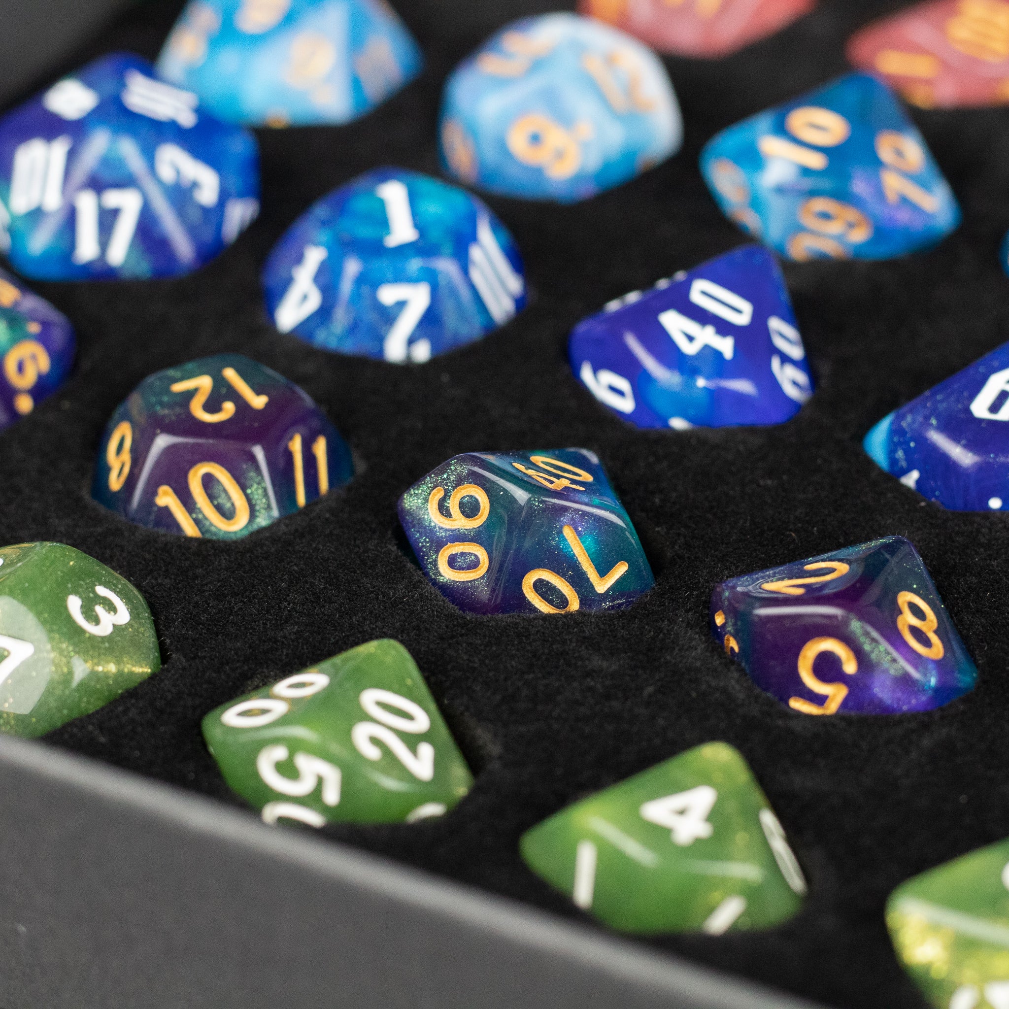 Acrylic Dice Set Gift Box - Blue and green acrylic polyhedral dice with gold and white numbers in a black velvet-lined gift box.