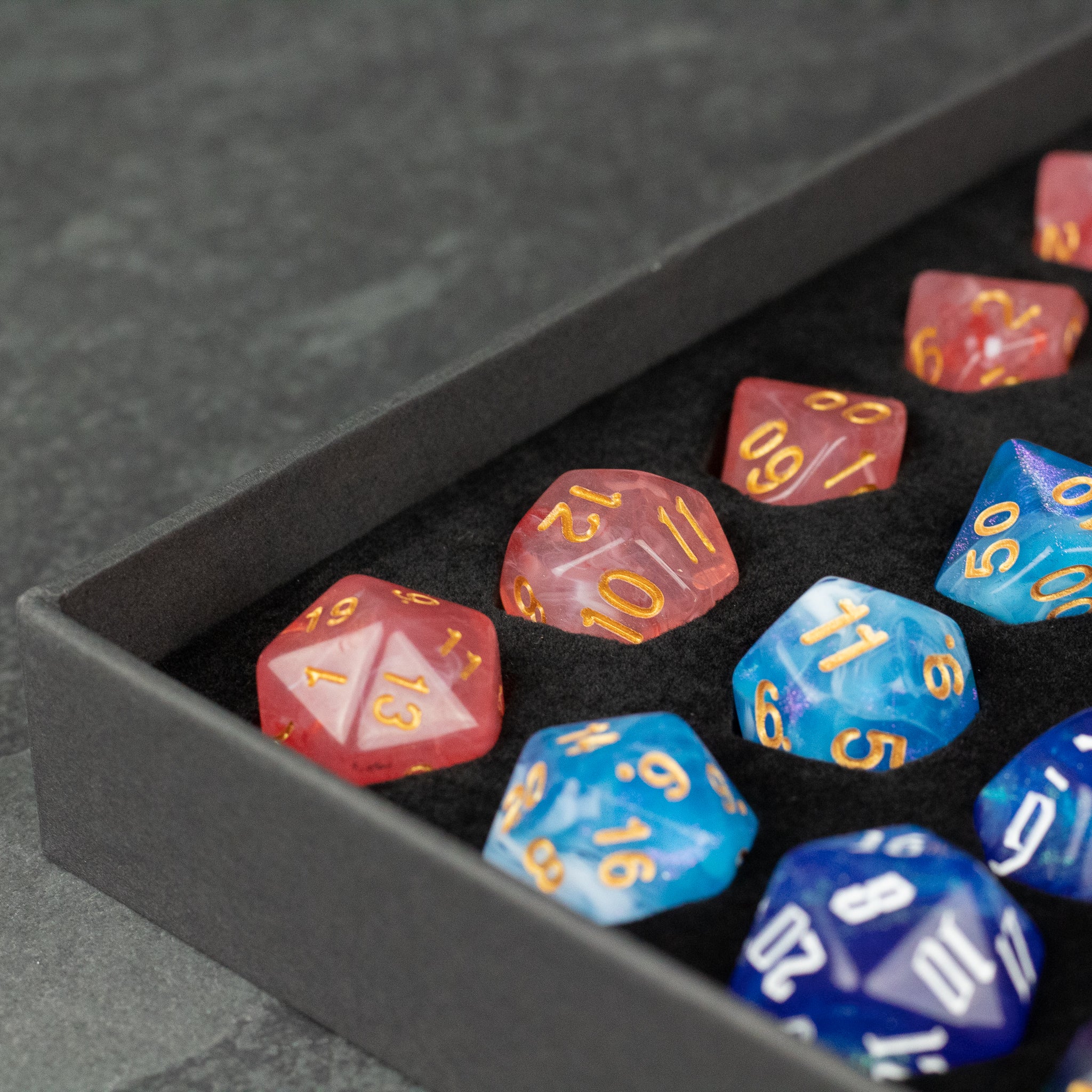 Acrylic Dice Set Gift Box - Set of translucent red, blue, and dark blue acrylic polyhedral dice with gold and white numbering in black gift box.