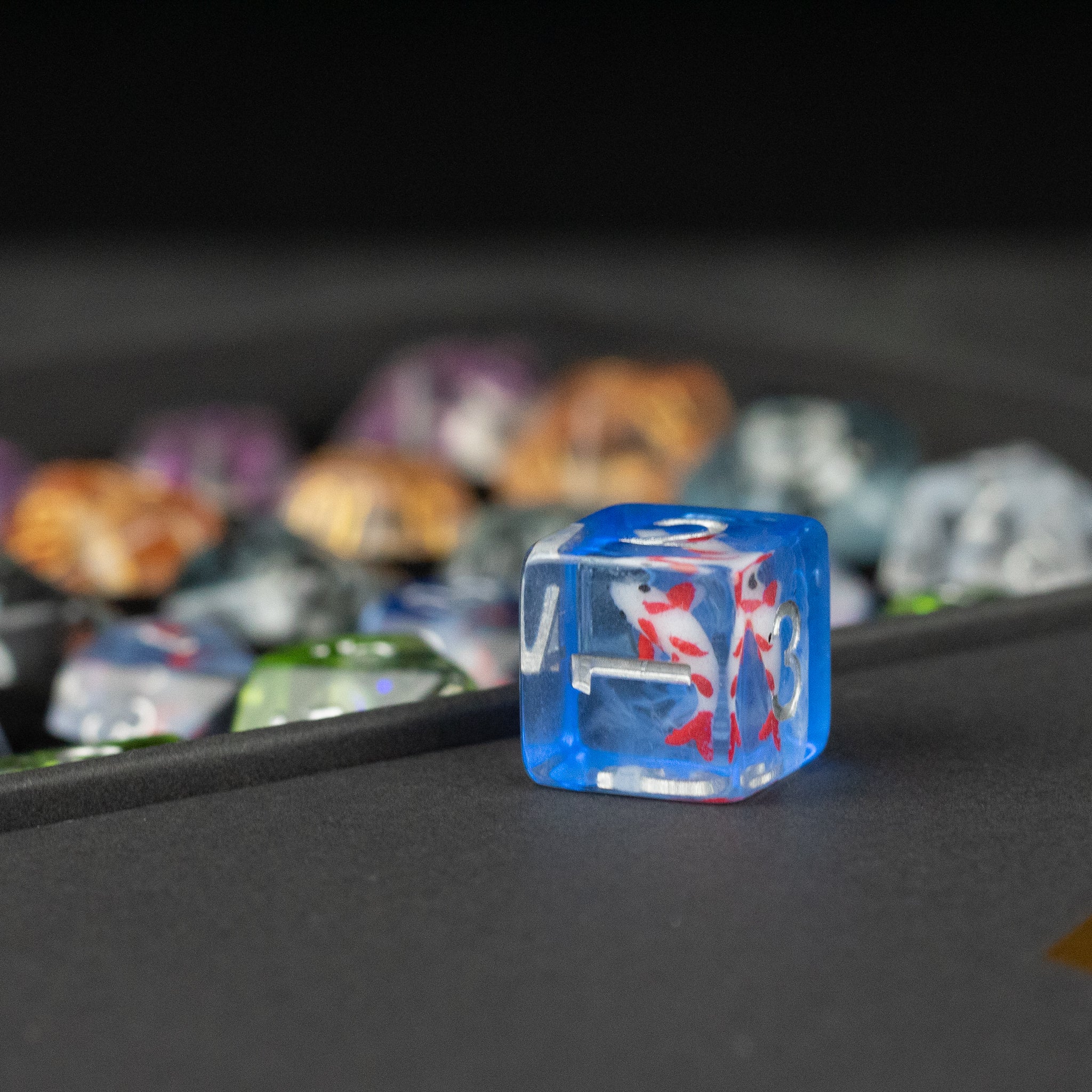 Koi Fish Dice Set Gift Box - Transparent blue six-sided die with a red and white koi fish design inside, displayed on a black surface with blurred.