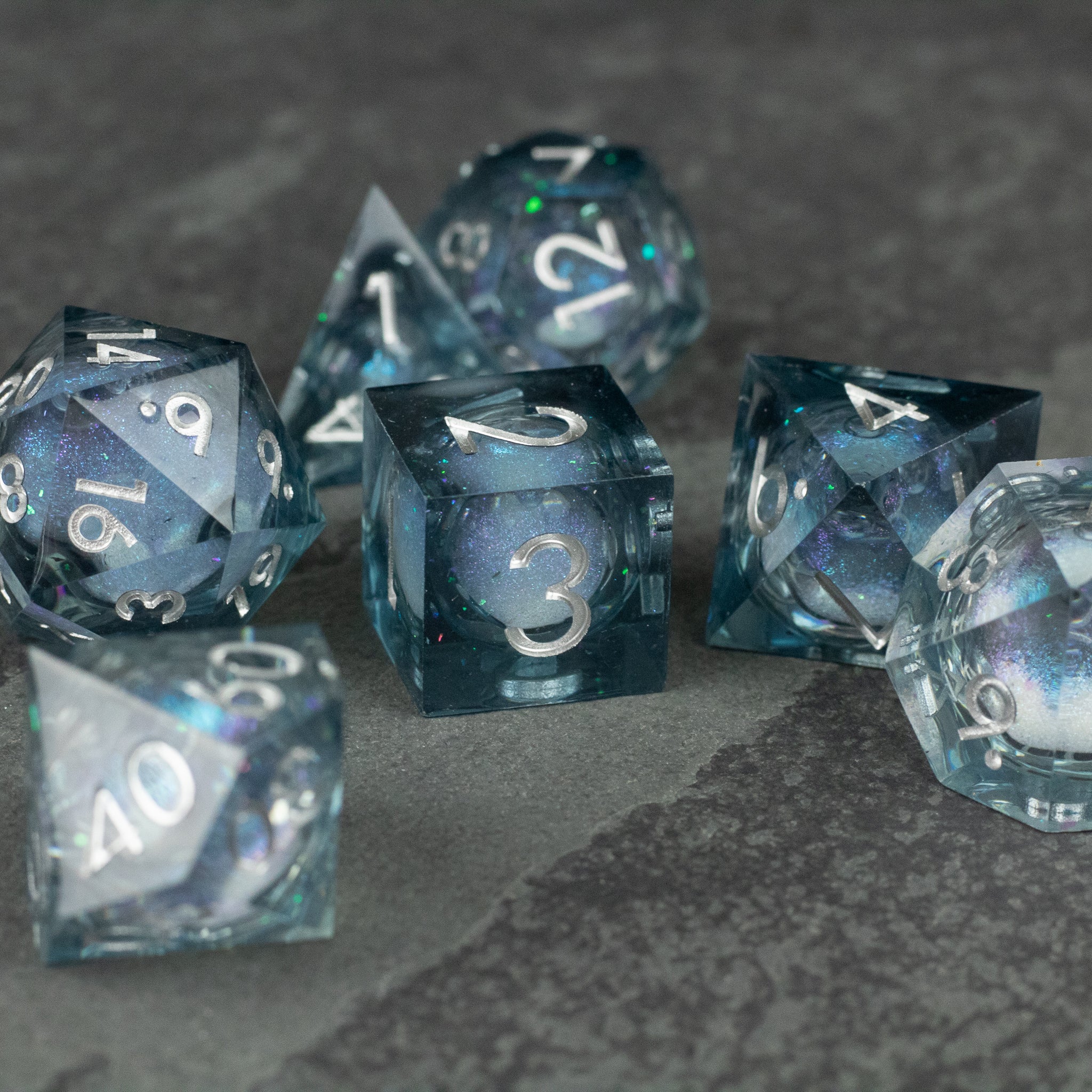 Astral Sea Liquid Core Dice Set - Translucent blue liquid core dice set with sharp edges and white numbering, including d20, d12, d10, d8, d6, and d4 shapes.