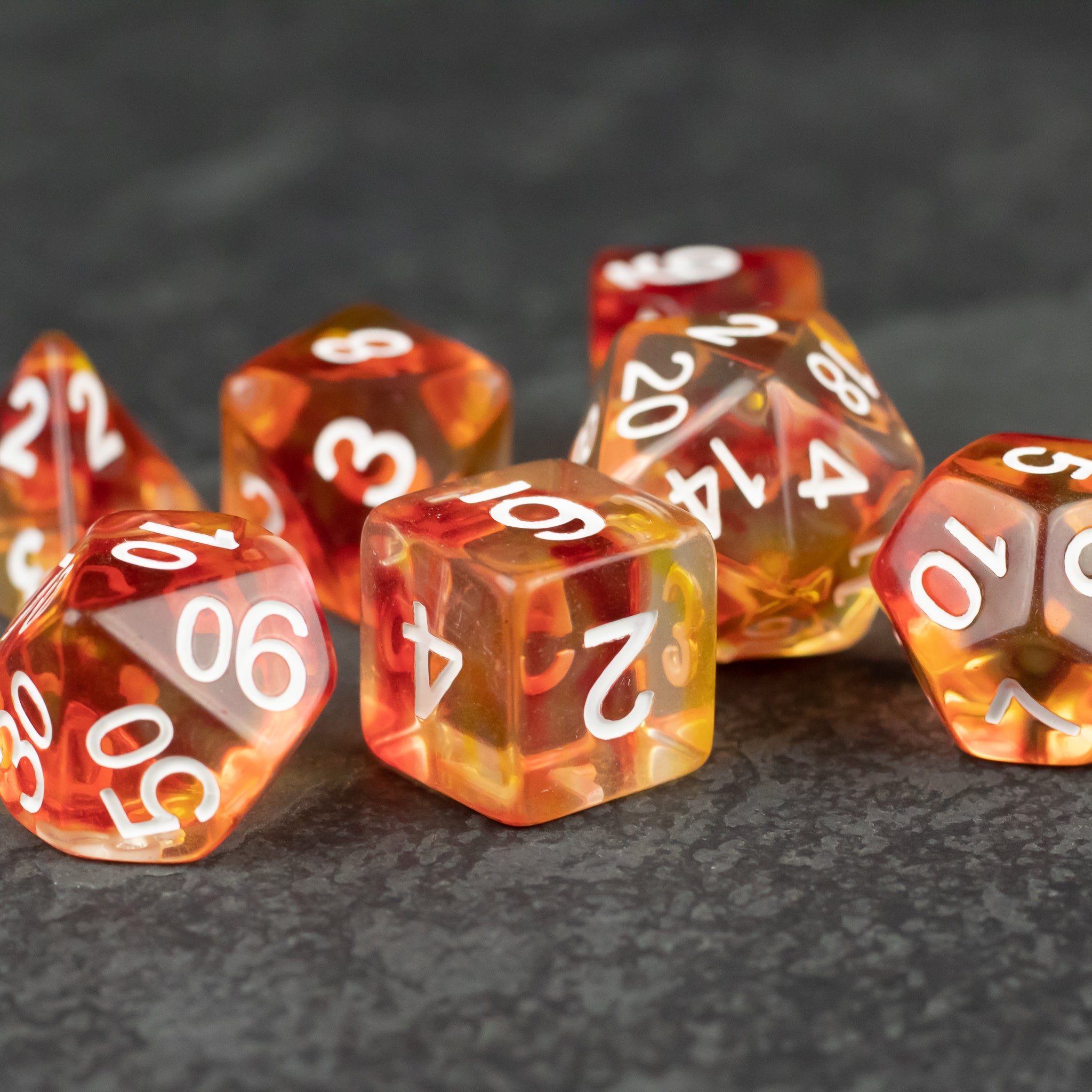 Magma Dice Set - Transparent orange and yellow polyhedral dice set with white numbers, including d20, d12, d10, d8, d6, and d4 shapes.