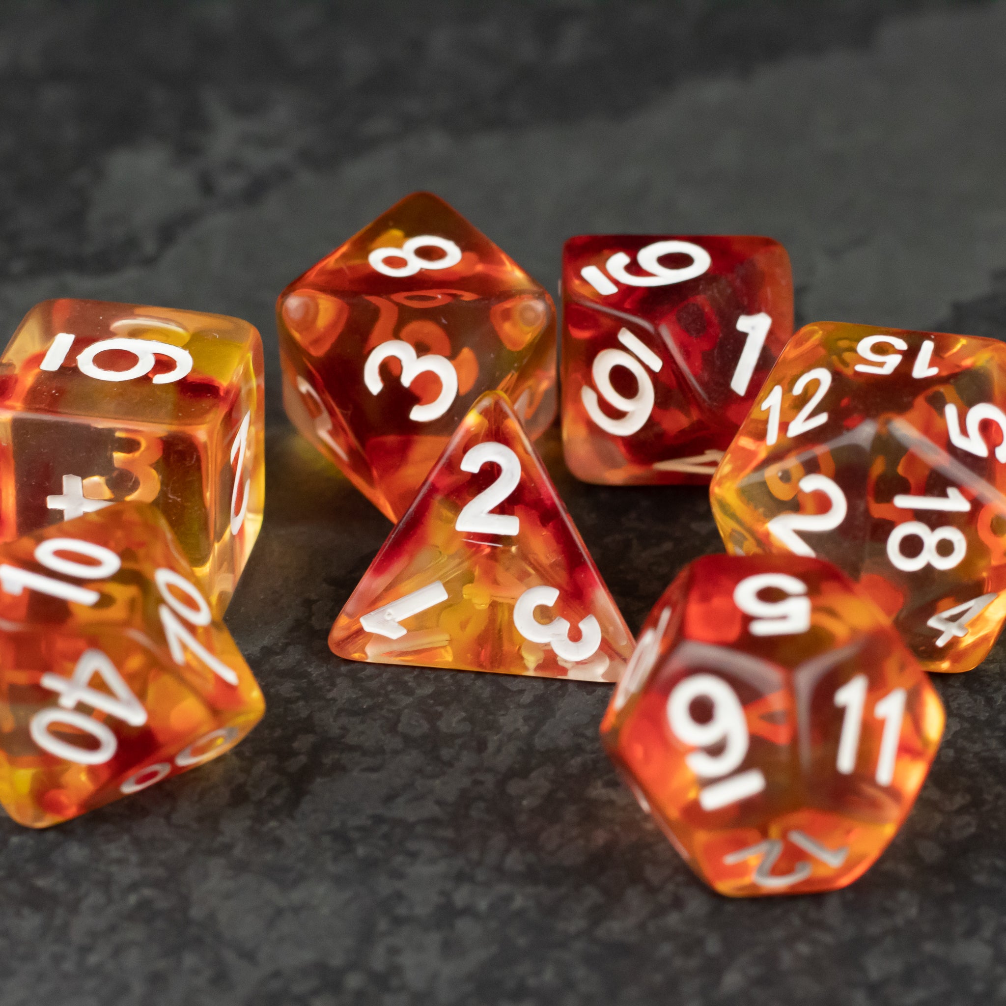 Magma Dice Set - Translucent red and orange polyhedral dice set with white numbers on a dark textured surface.