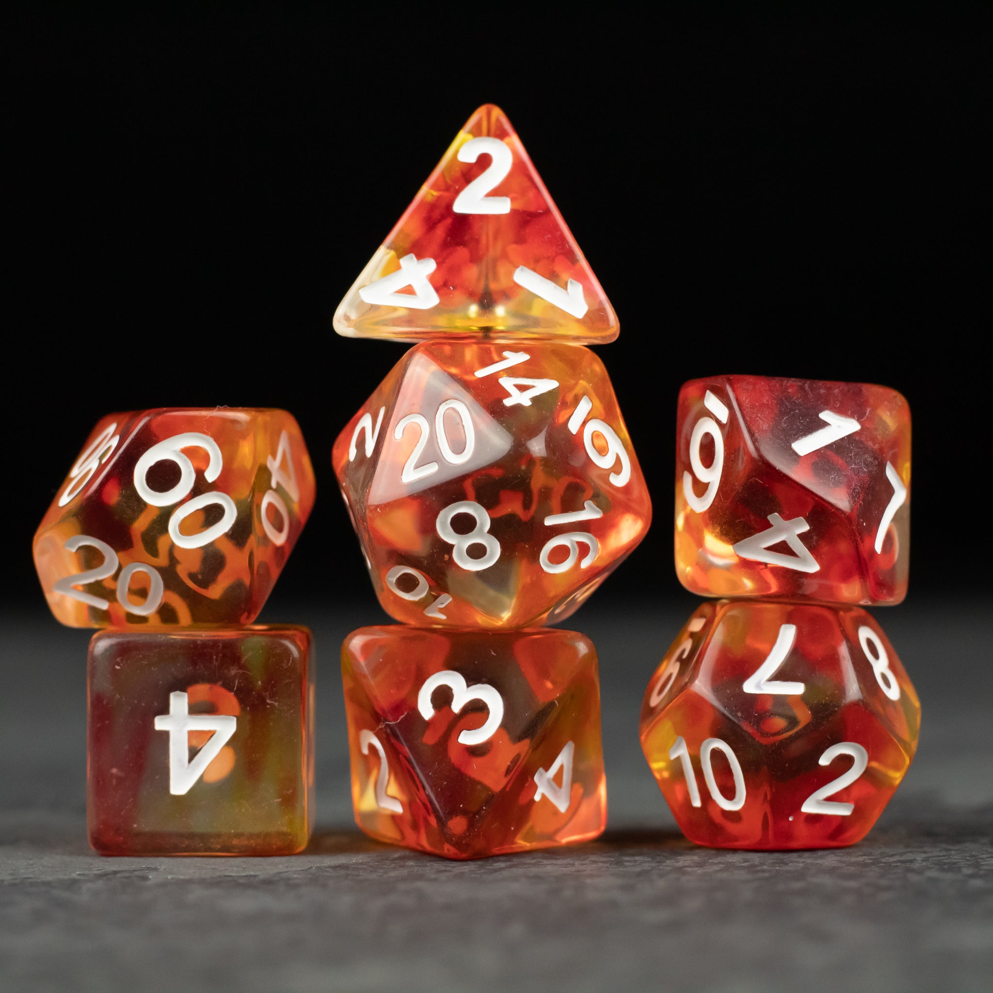 Magma Dice Set - Seven polyhedral dice in fiery red and orange with white numbers, including d20, d12, d10, d8, d6, and d4.