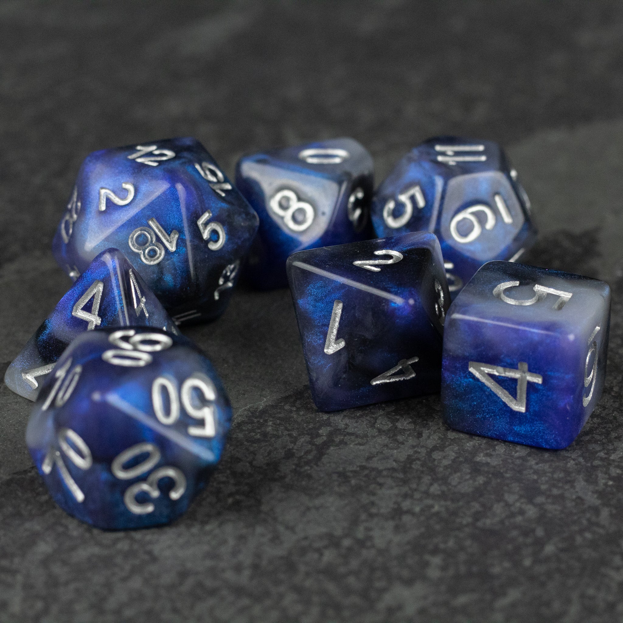 Cosmic Dust Dice Set - Set of seven blue and purple marbled polyhedral dice with white numbering for tabletop games.