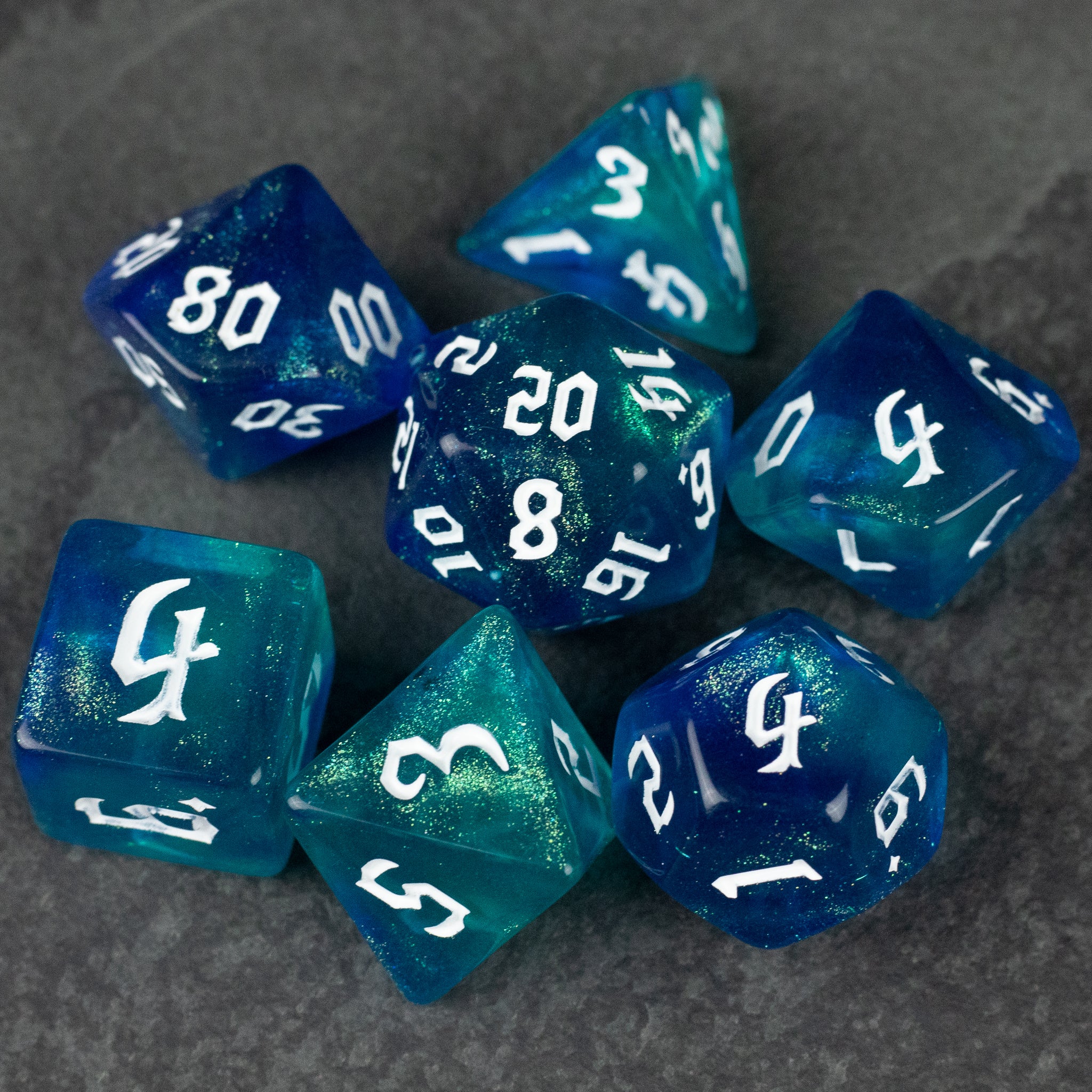 Blue & Green Glitter Dice Set - Set of seven polyhedral dice with blue and green glitter swirl and white numbering.