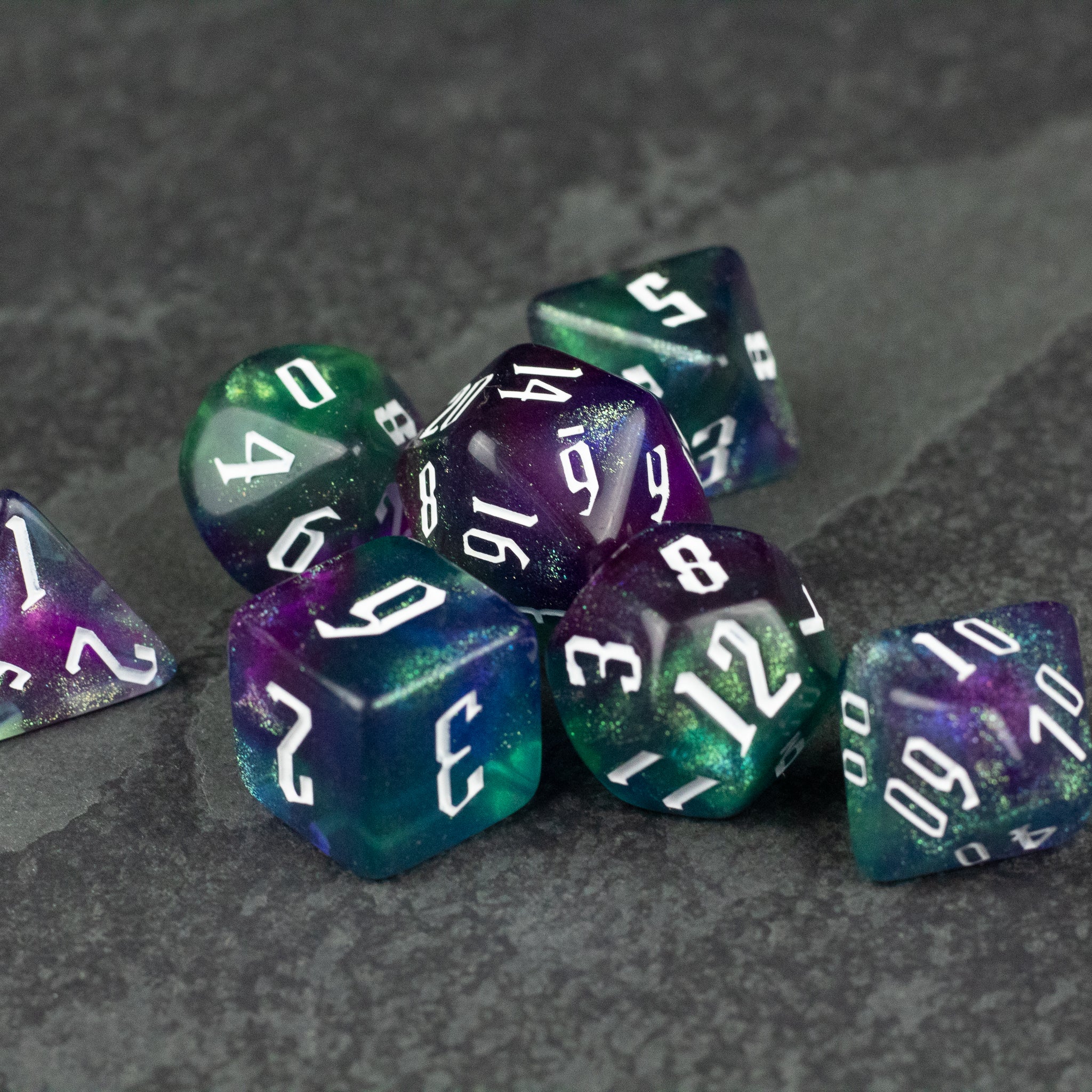Purple & Green Glitter Dice Set - Set of purple and green translucent glitter dice with white numbering, including d4, d6, d8, d10, d12, and d20 shapes on a.