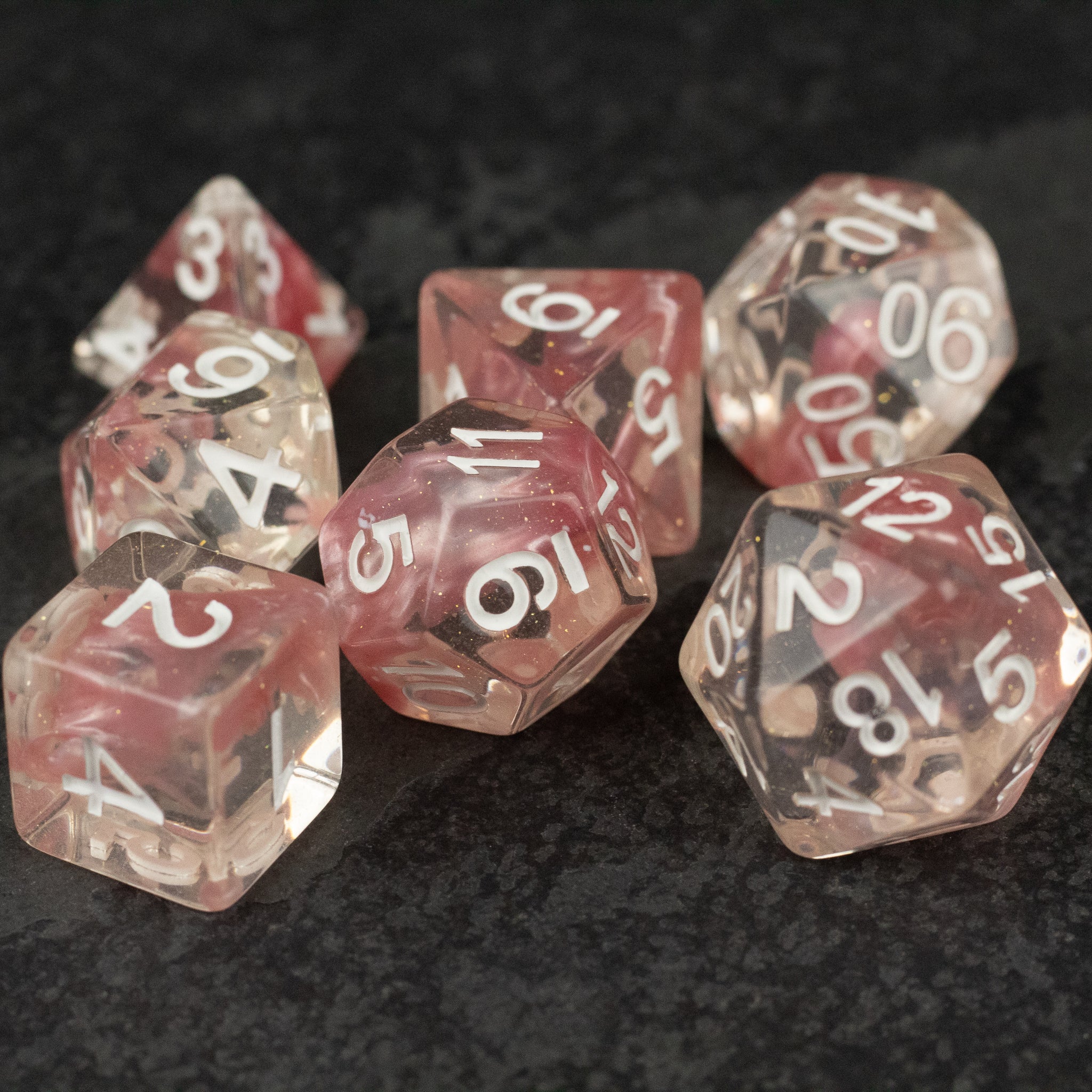 Pink Lava Lamp Dice Set - Seven translucent pink dice with white numbering, featuring a smoky lava lamp effect.