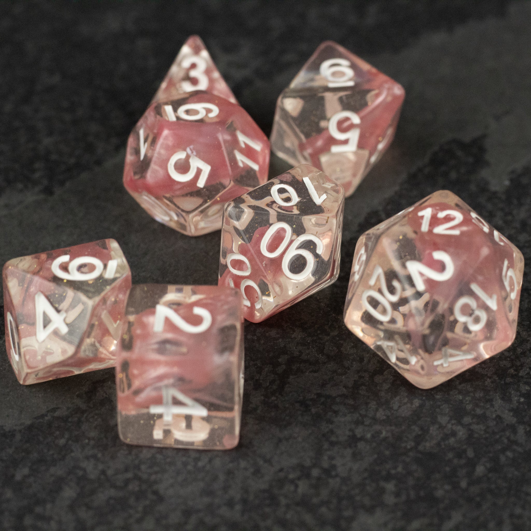 Pink Lava Lamp Dice Set - Set of six translucent pink dice with swirled lava-like patterns and white numbers on a dark surface.