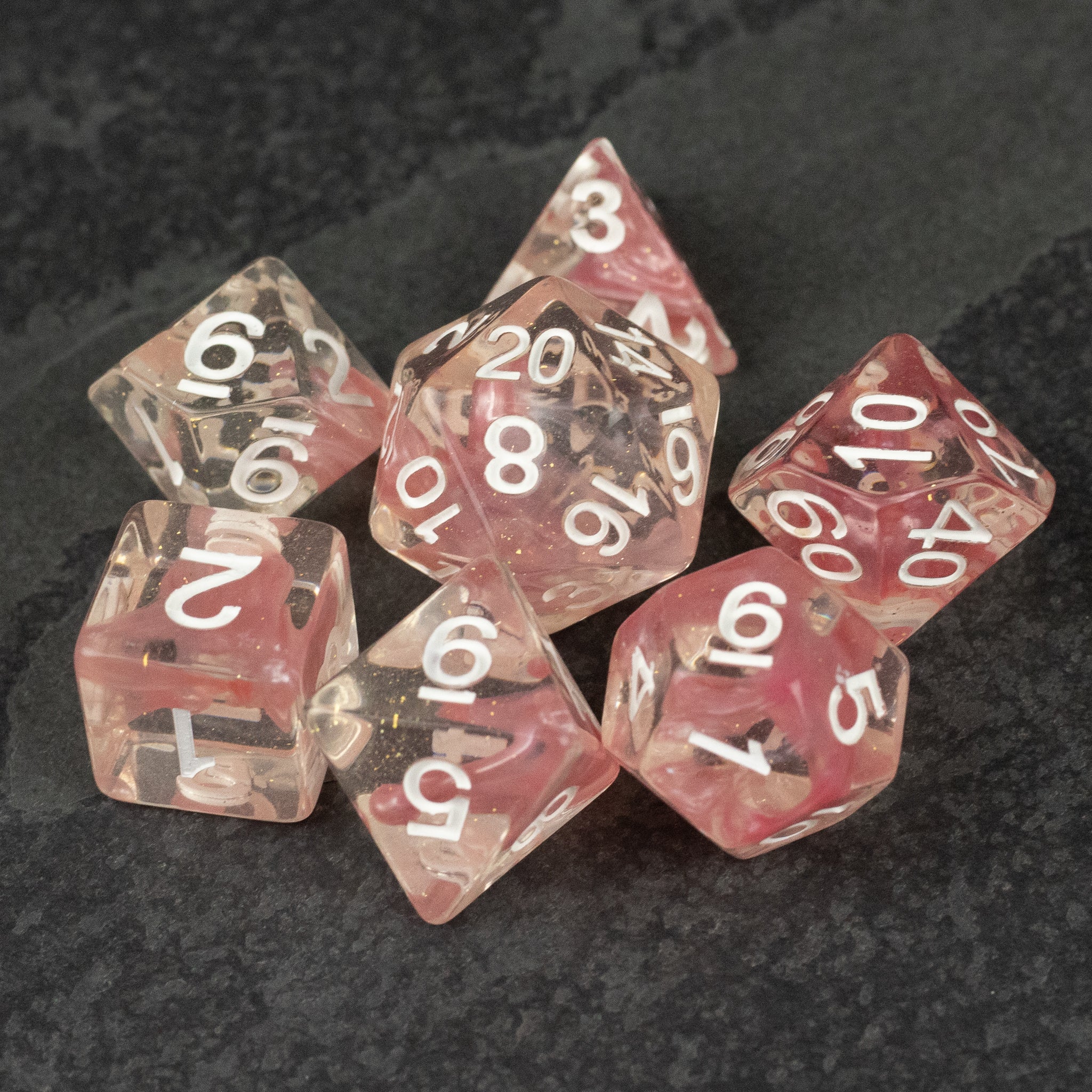 Pink Lava Lamp Dice Set - Set of seven translucent pink lava lamp style polyhedral dice with white numbers on dark surface.