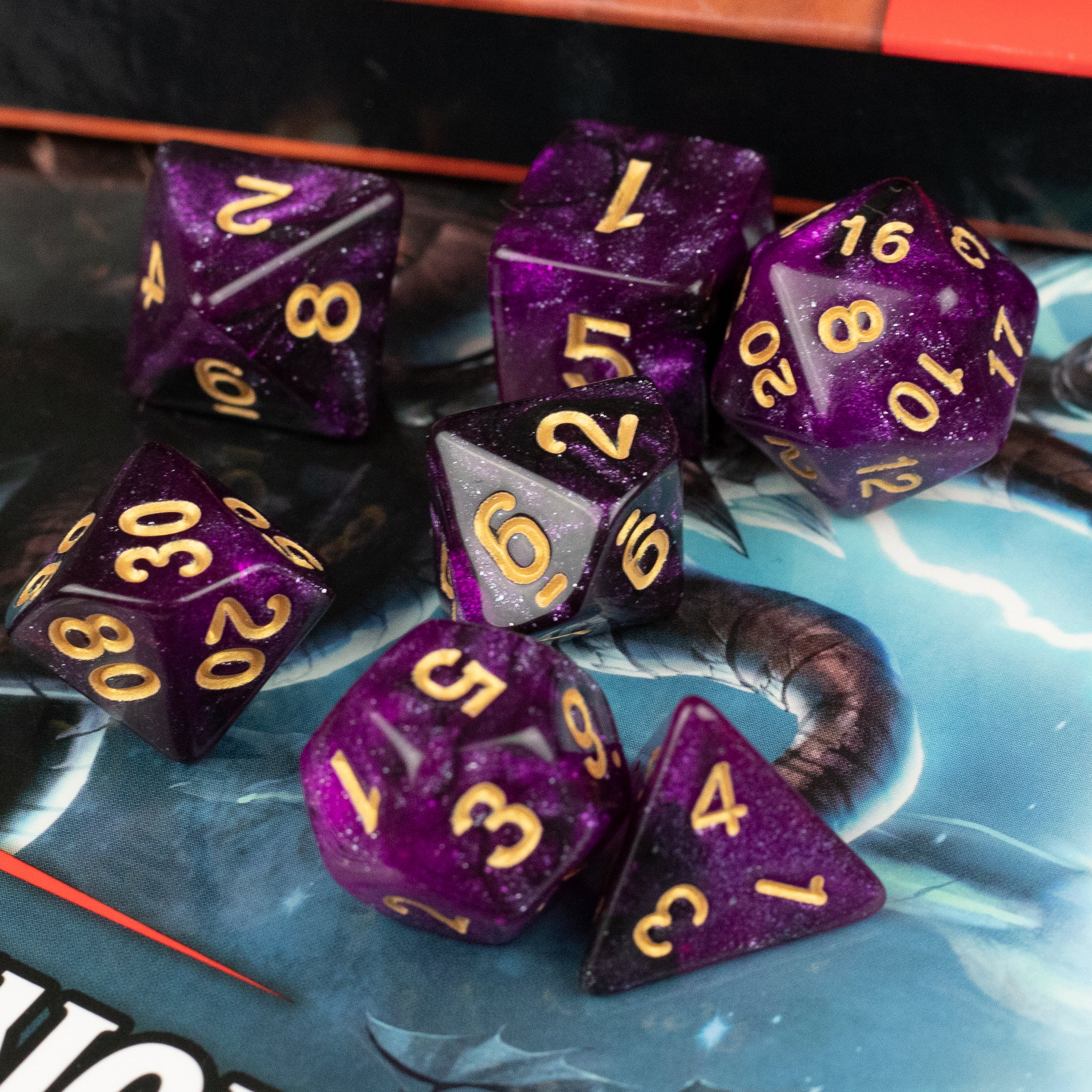 Purple and Black Glitter Dice Set - Seven purple glitter dice with gold numbers on a gaming mat, including d20, d12, d10, d8, d6, and d4 shapes.