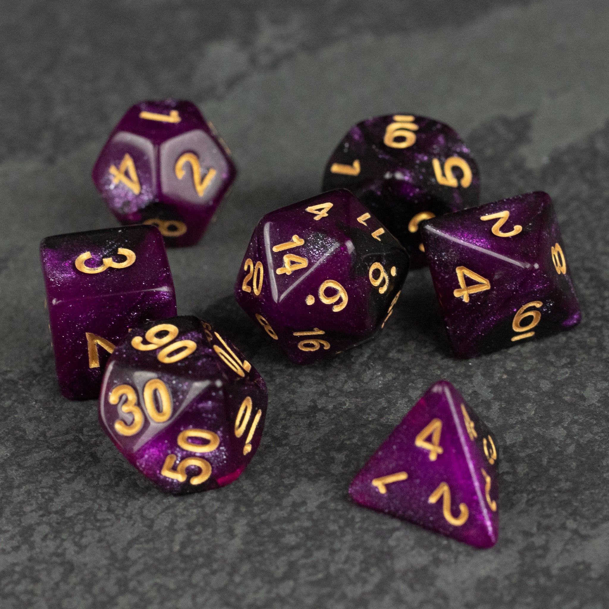 Purple and Black Glitter Dice Set - Seven purple dice with black glitter and gold numbers, featuring various polyhedral shapes for gaming.