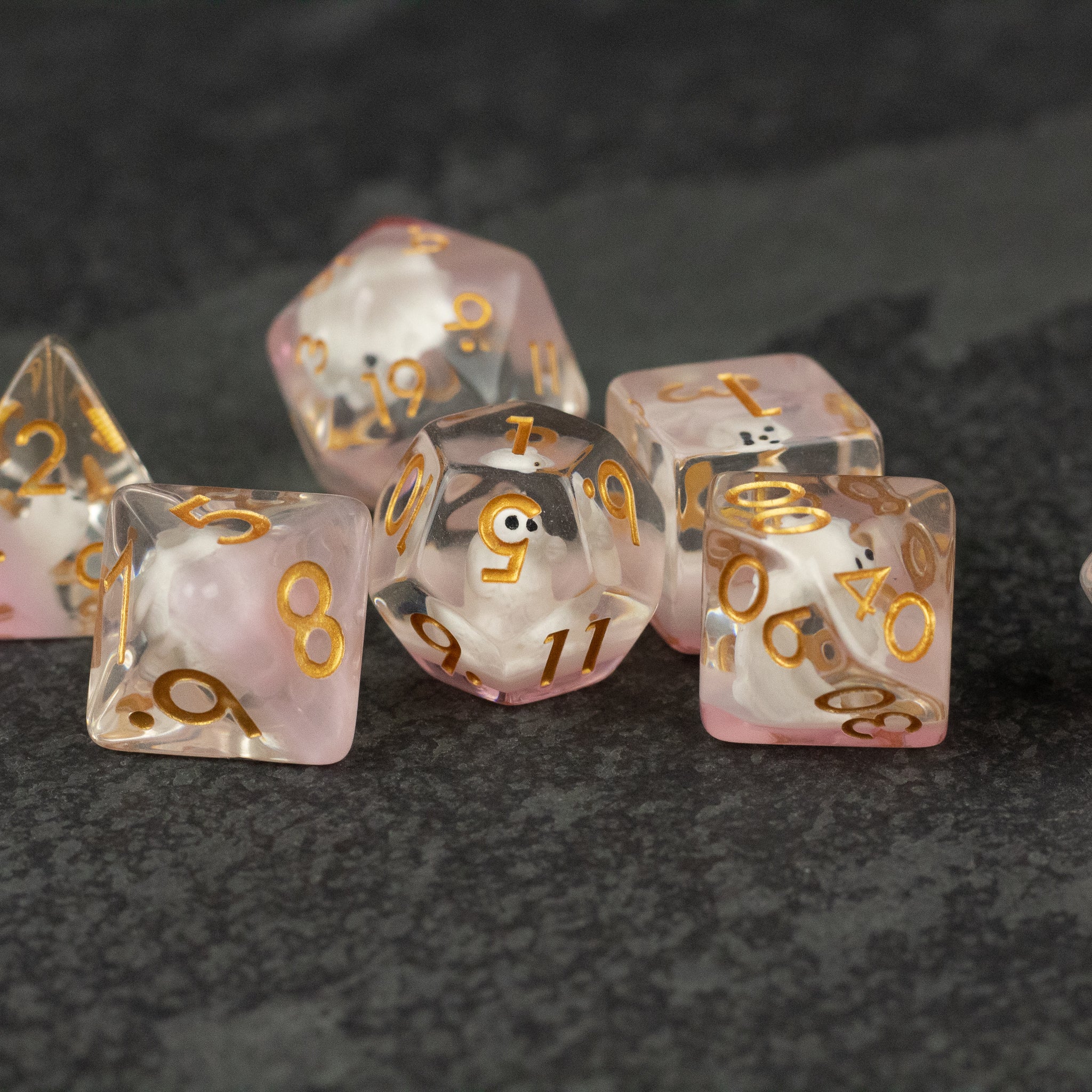 Polar Bear Dice Set - Translucent white and pink dice set with gold numbers, including d20, d12, d10, d8, d6, and d4 on a dark textured surface.
