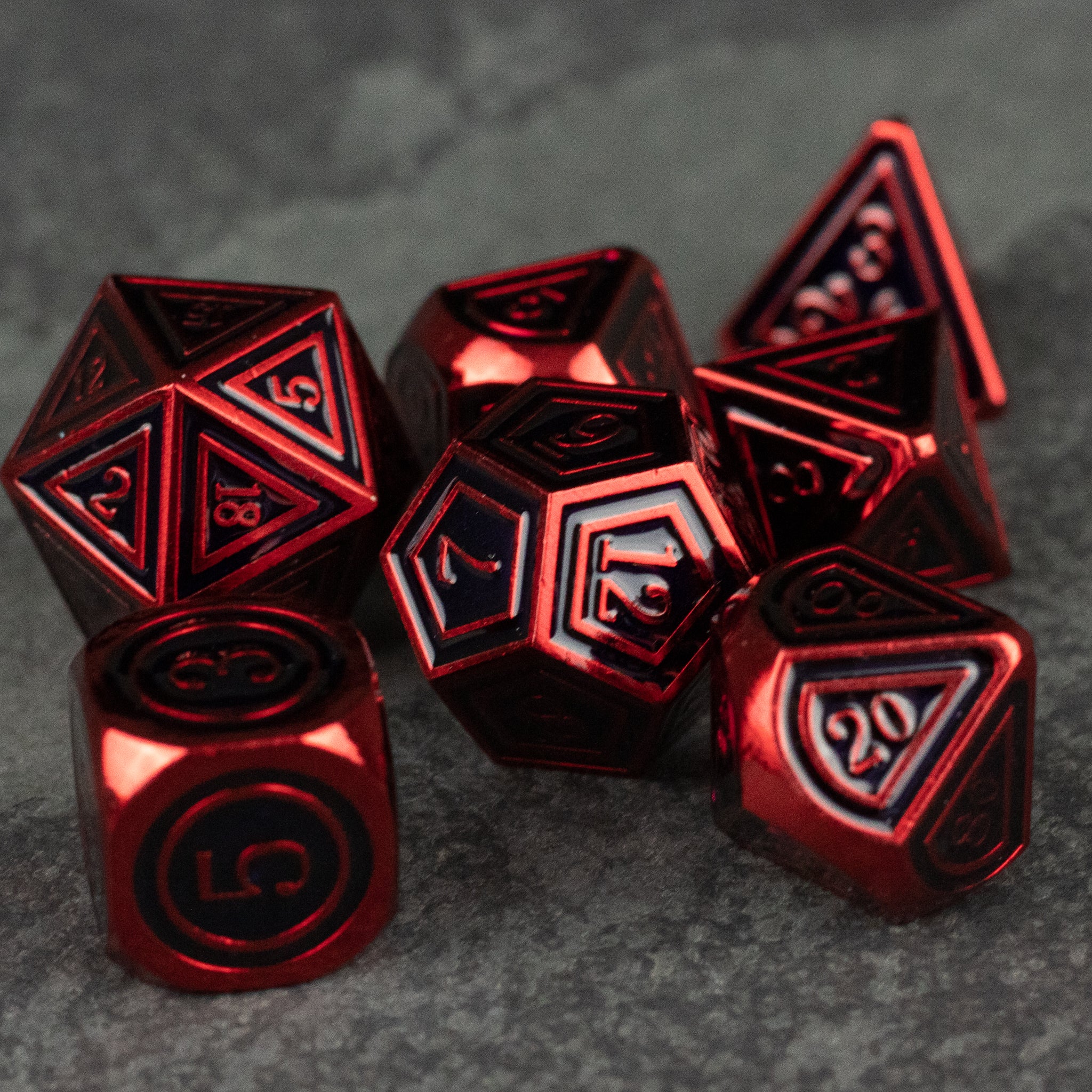 Crimson Ritual Dice Set - Glossy red metal polyhedral dice set with black engraved numbers on textured gray surface.