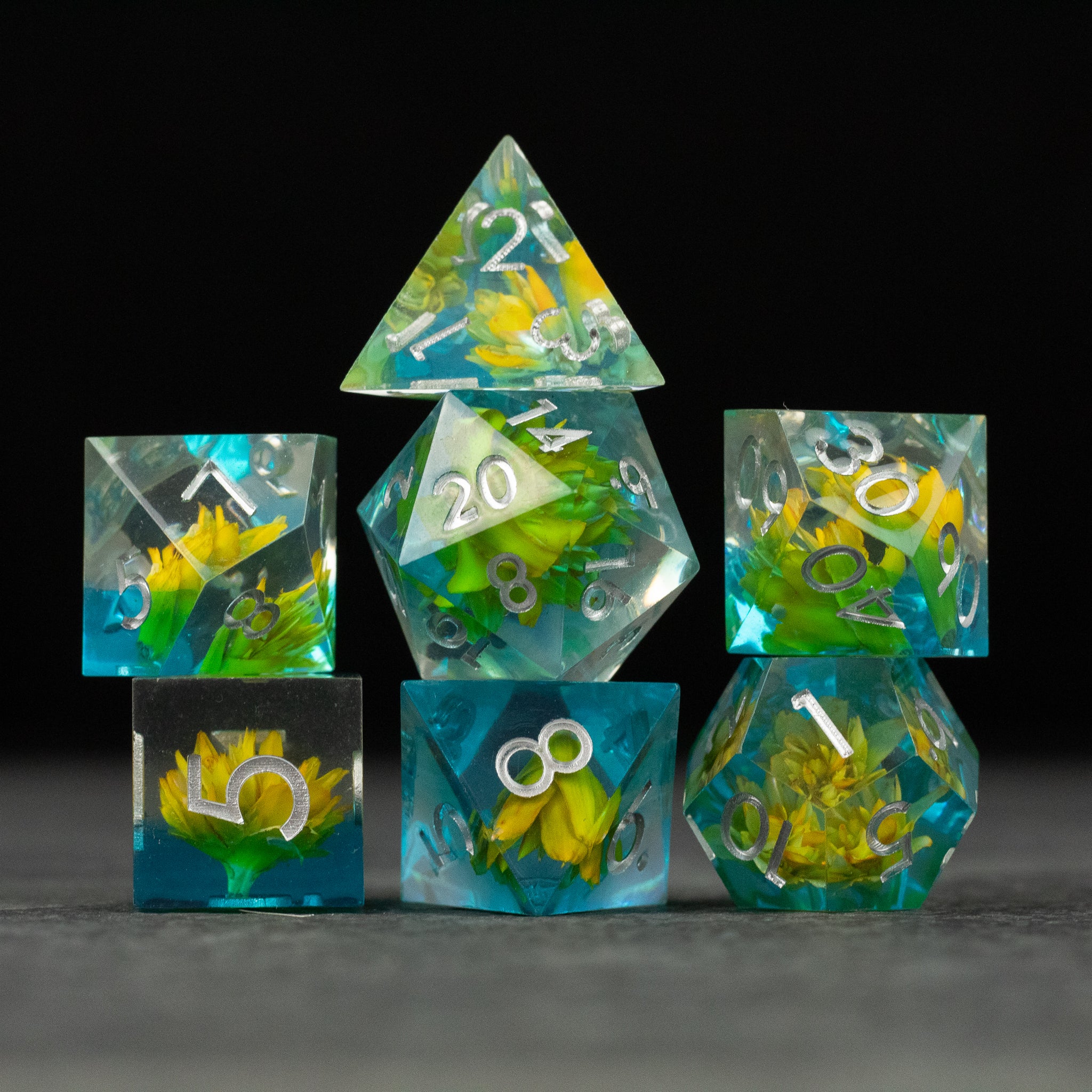 Yellow Flower + Blue Resin Sharp Edge Dice Set - Set of sharp-edged dice with yellow flowers embedded in blue and clear resin, white numbering.