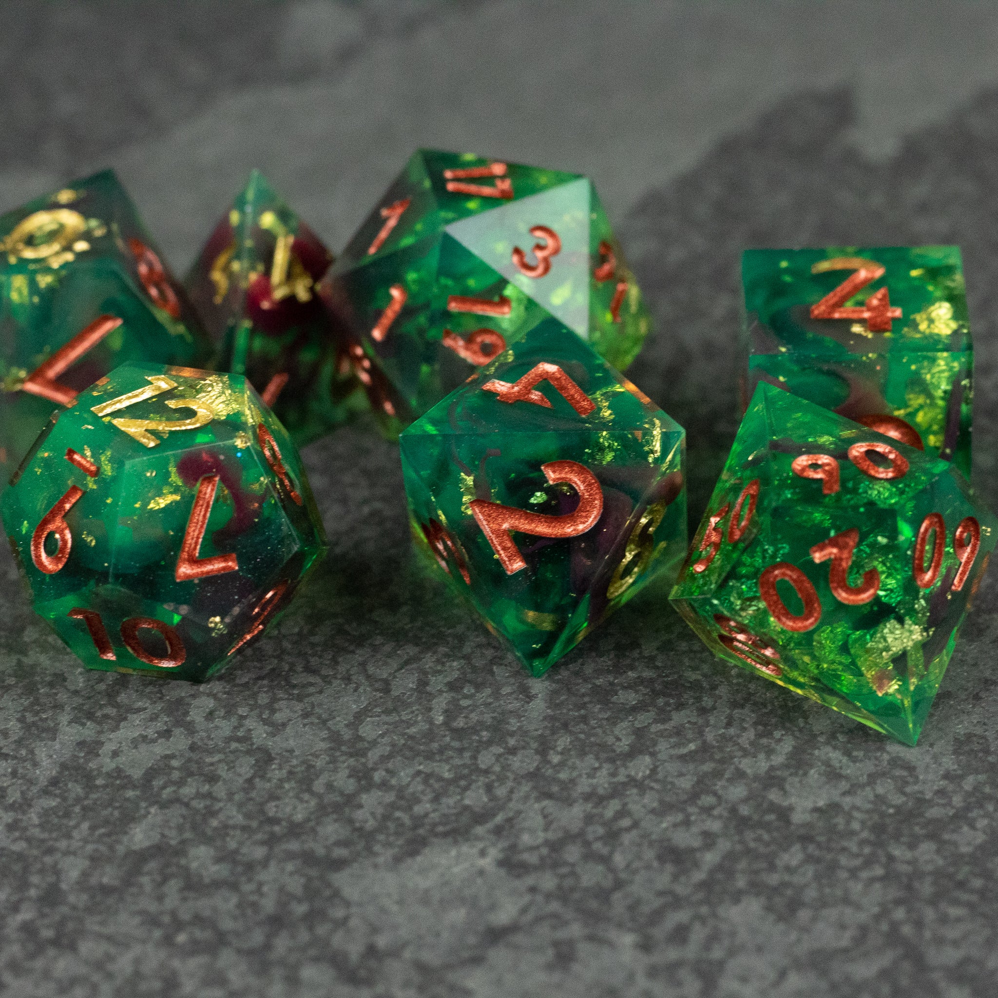 Primal Blood Dice Set - Set of translucent green sharp-edged polyhedral dice with glowing gold numbers.