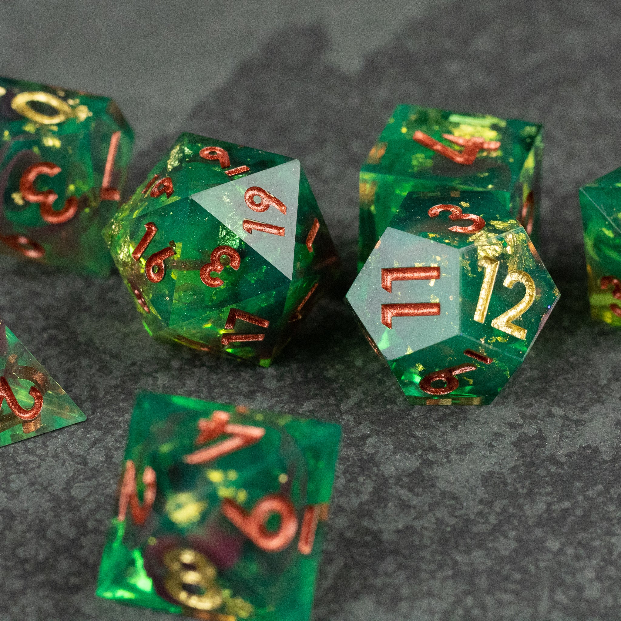 Primal Blood Dice Set - Translucent green twenty-sided dice with sharp edges and red-gold numbering on a dark textured surface.