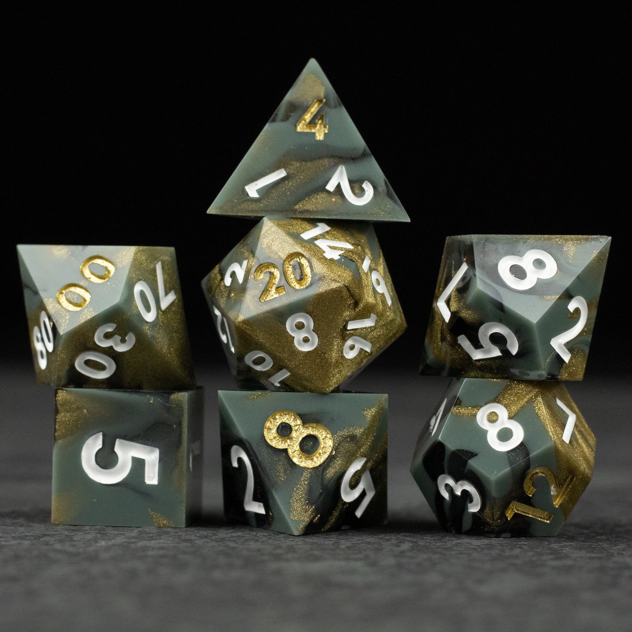 Greedfall Dice Set - Set of seven polyhedral dice in dark green and gold with sharp edges and white numbering.