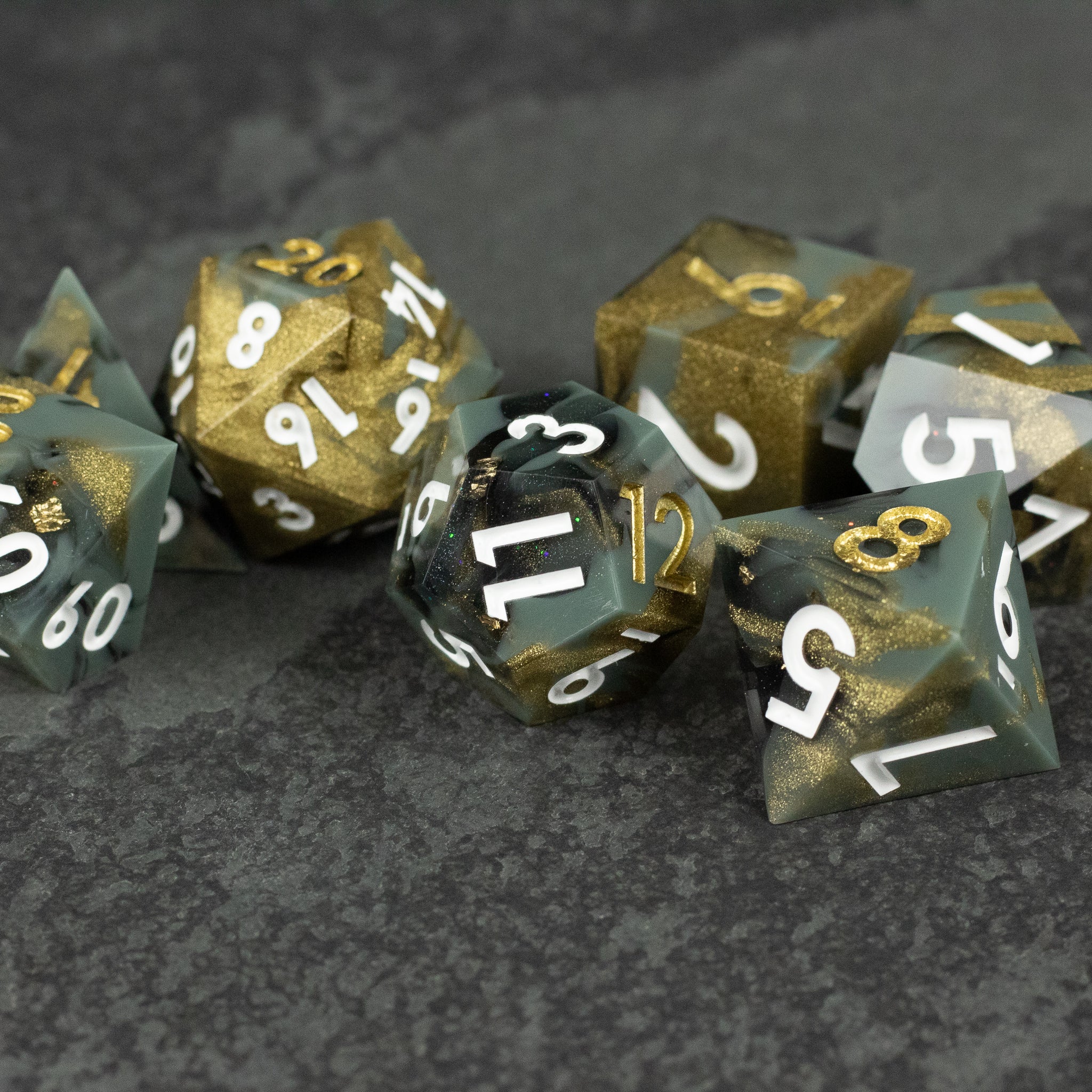 Greedfall Dice Set - Set of seven sharp-edged polyhedral dice in smoky black and gold with white numbering.
