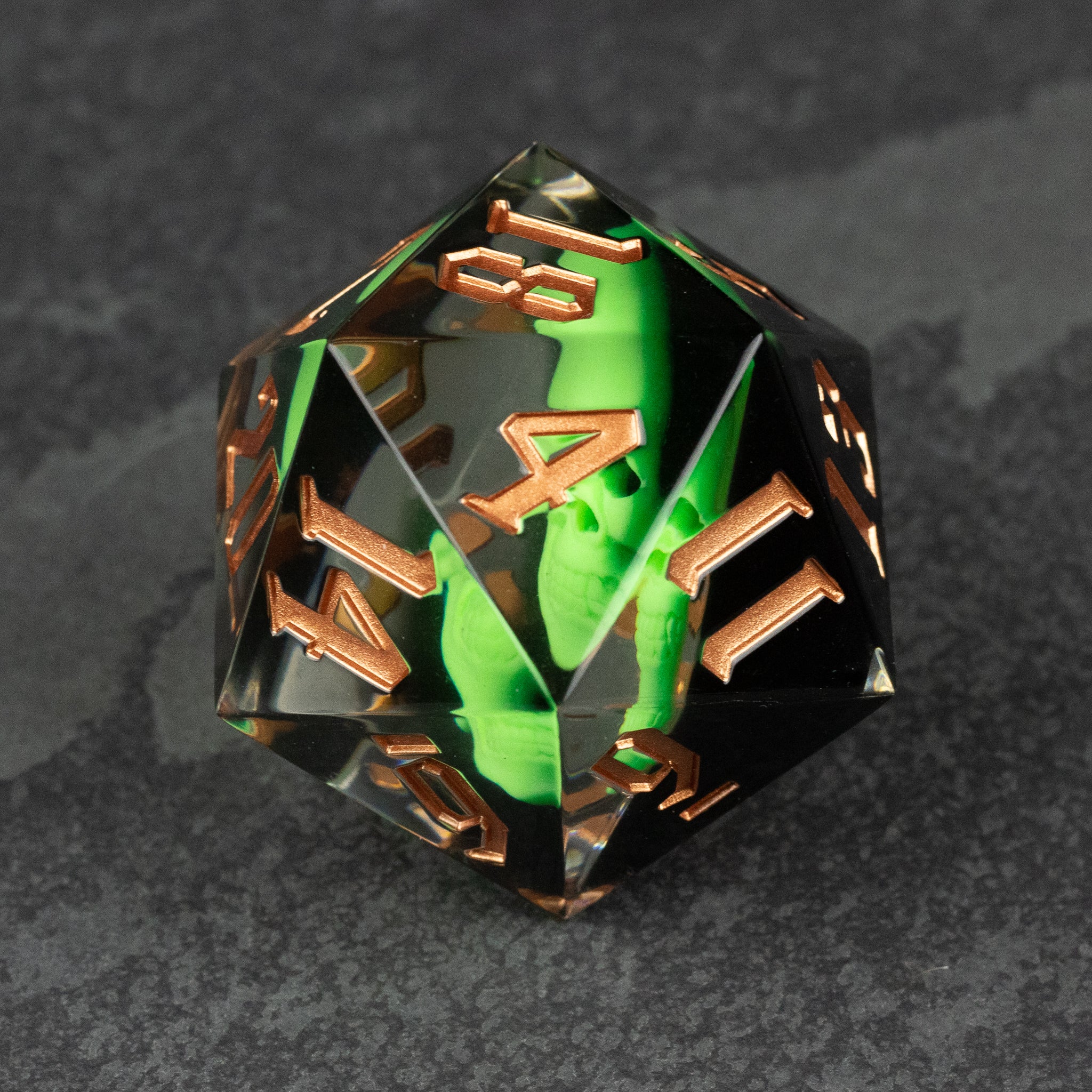 Giant 55mm D20 - Glowing Skull - Transparent resin 55mm D20 dice with glowing green skull inside and bronze metallic numbers.