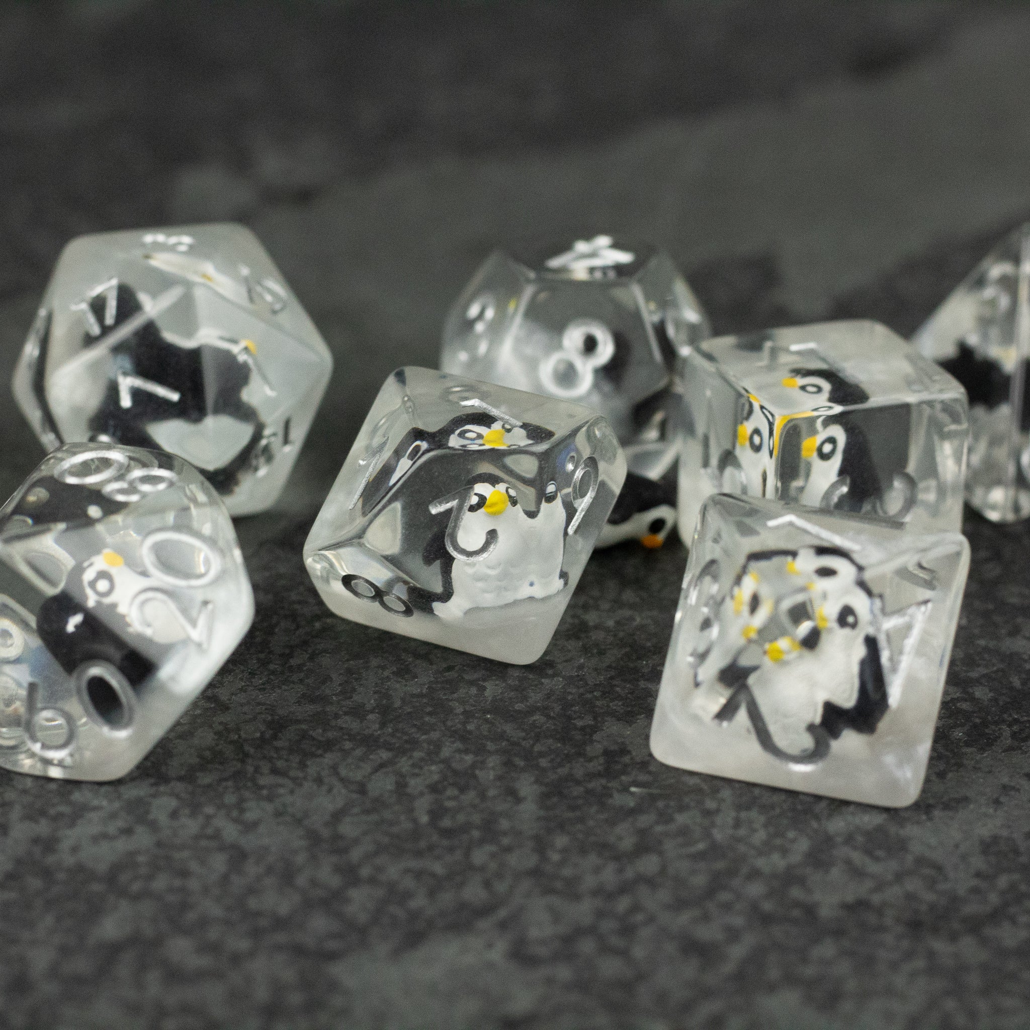 Penguin Dice Set - Clear polyhedral dice set with black and white penguin illustrations and yellow accents on numbers.