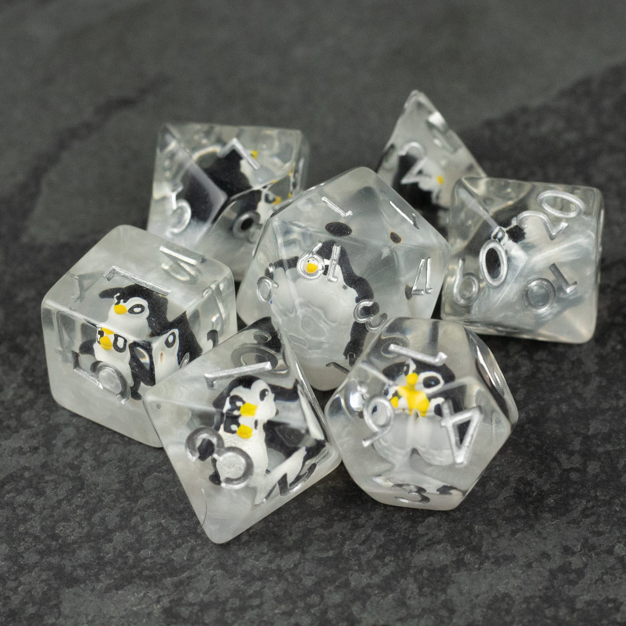 Penguin Dice Set - Clear polyhedral dice set with embedded tiny black and white penguin figures and white numbers.