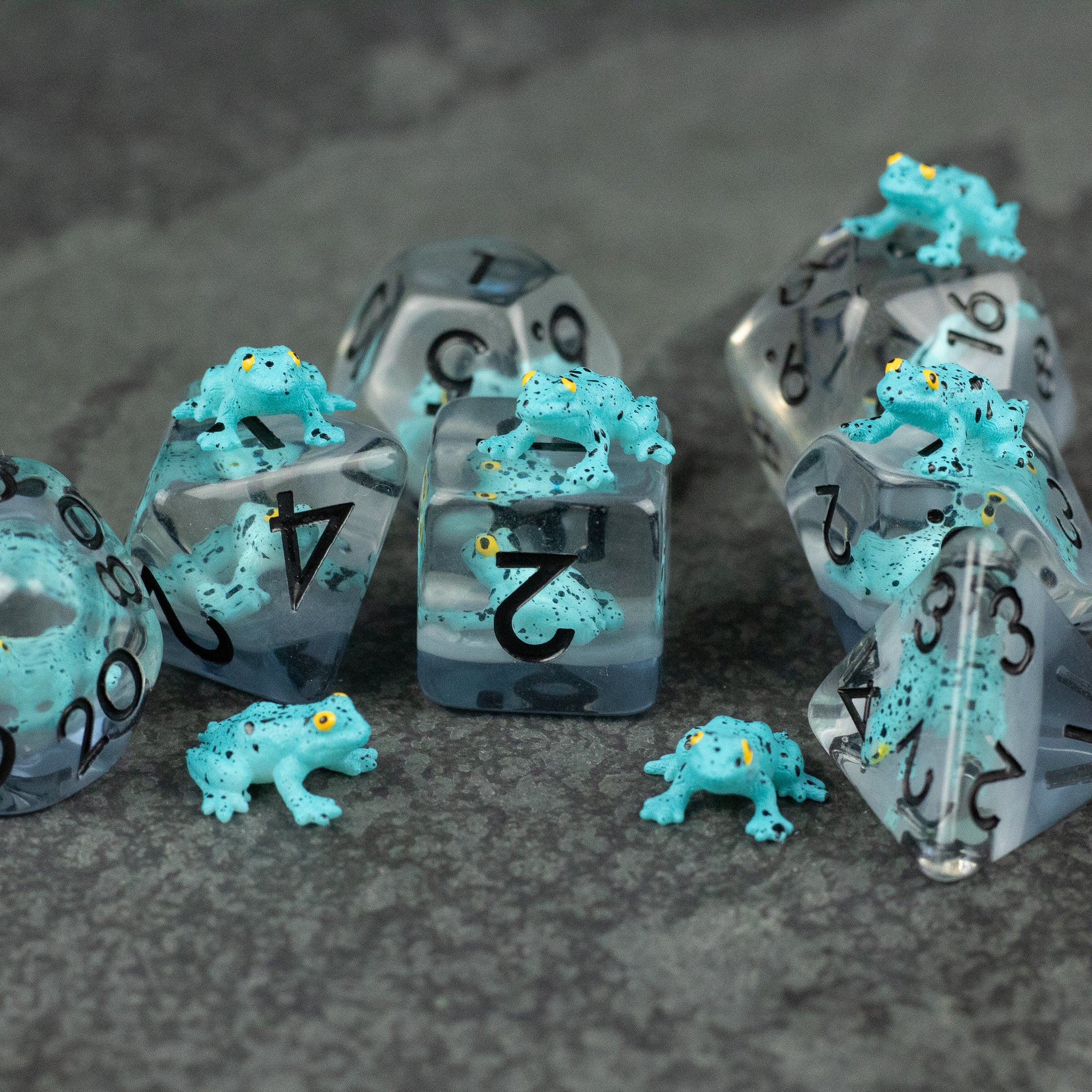 Blue Frog Dice Set - Translucent gray polyhedral dice set with small bright blue frog figurines on and around them.
