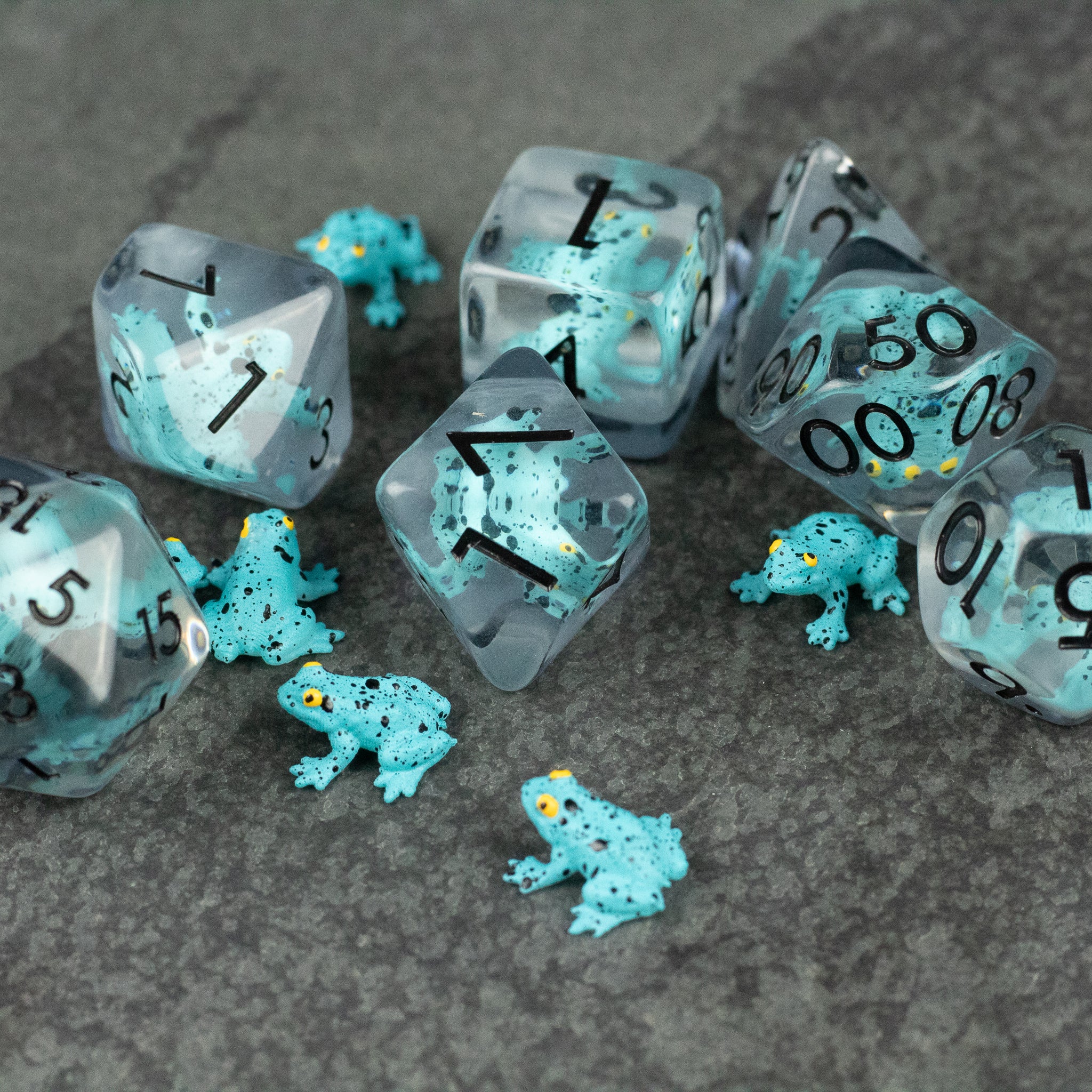 Blue Frog Dice Set - Translucent blue polyhedral dice with black numbers, each containing a miniature detailed blue frog inside, displayed on a.