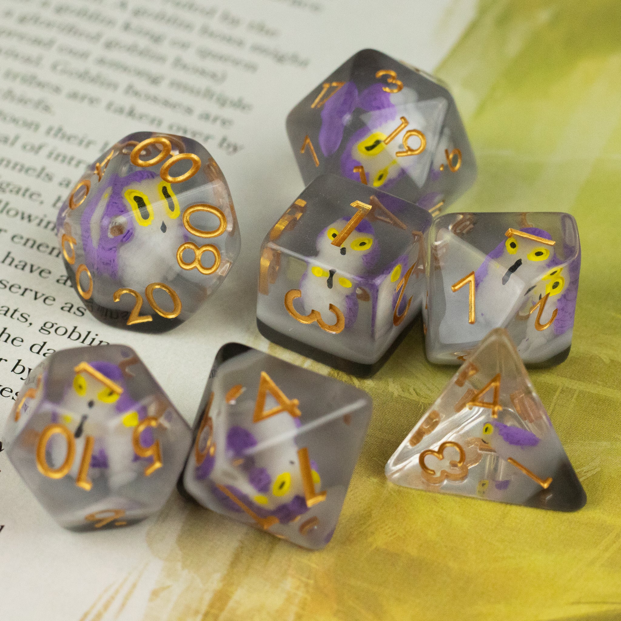 Purple Owl Dice Set - Seven translucent dice set with purple and white swirling inside, gold numbering, including various shapes like d20, d12,.