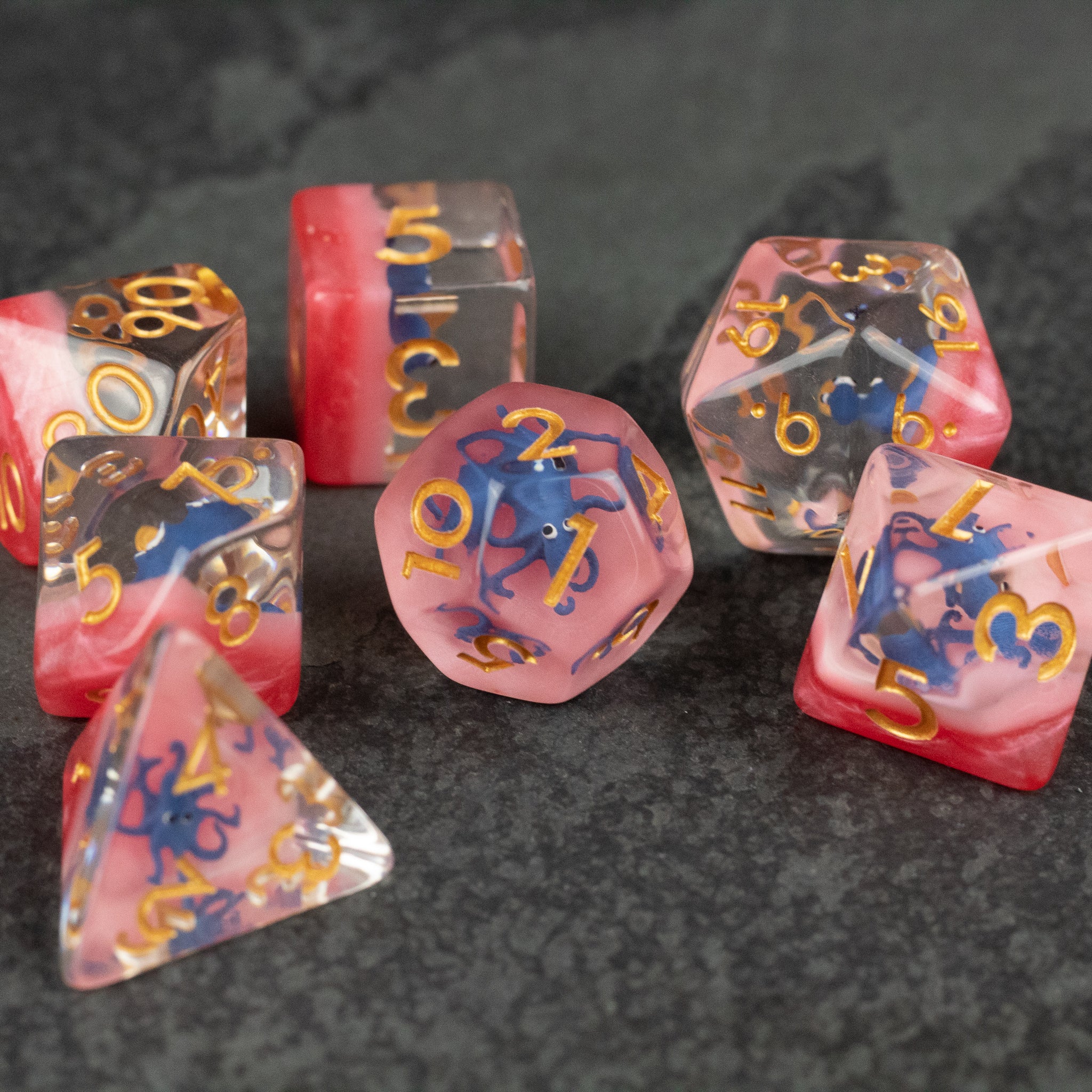 Dark Blue Octopus Dice Set - Seven-piece dice set with translucent dark blue and pink swirls, gold numbers, featuring various polyhedral shapes including