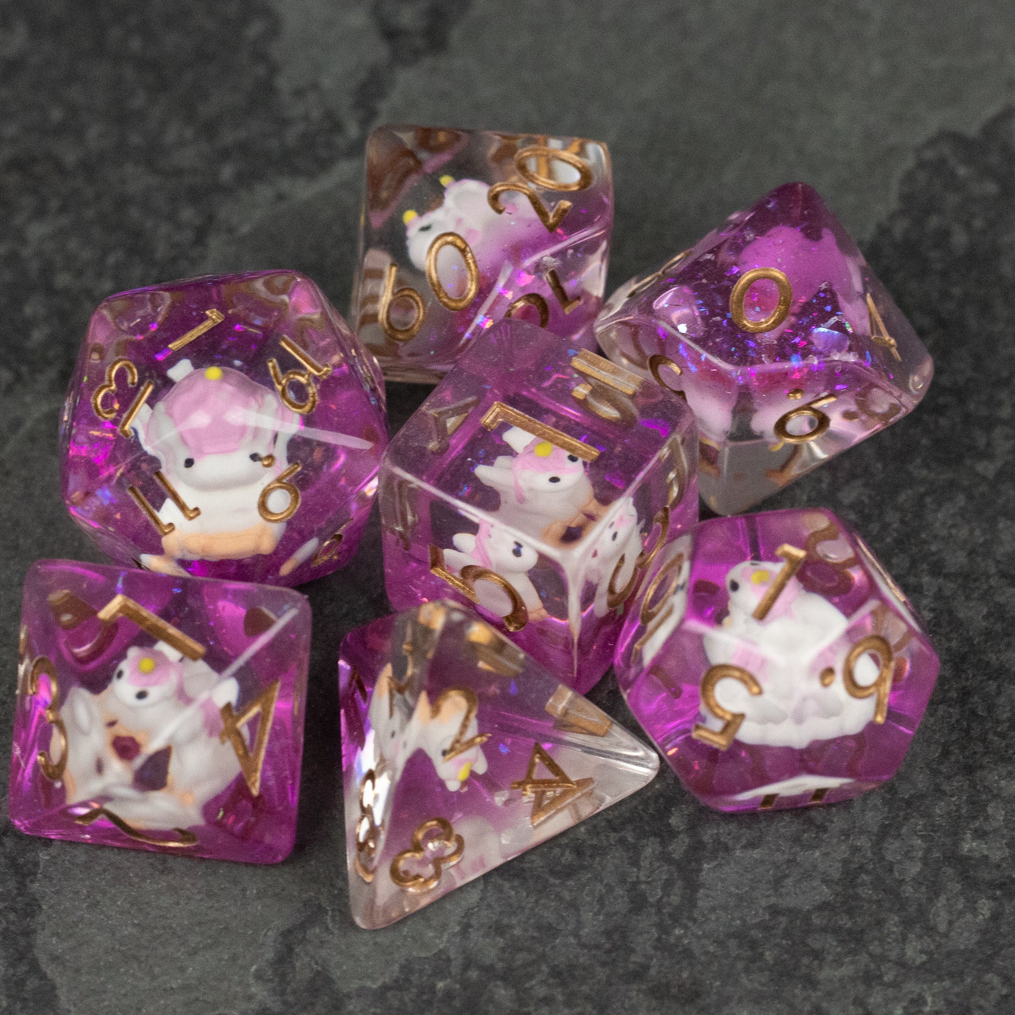 Pink Unicorn Dice Set - Transparent pink polyhedral dice set with gold numbers and white unicorn designs inside.