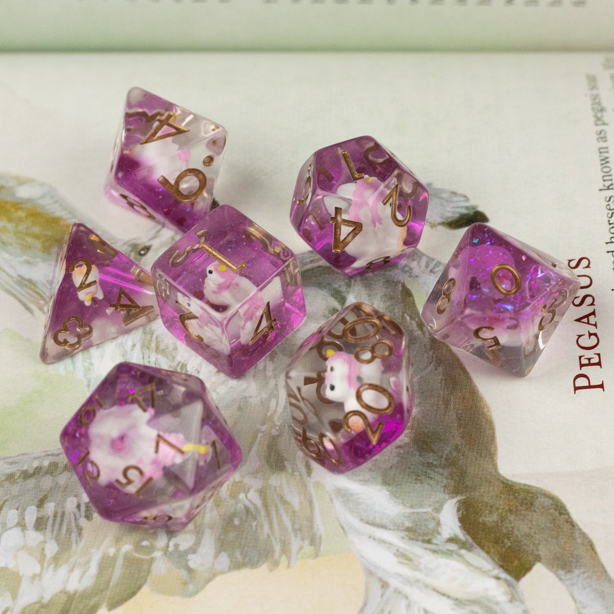 Pink Unicorn Dice Set - Translucent pink polyhedral dice set with gold numbers, featuring inclusions and glitter details.