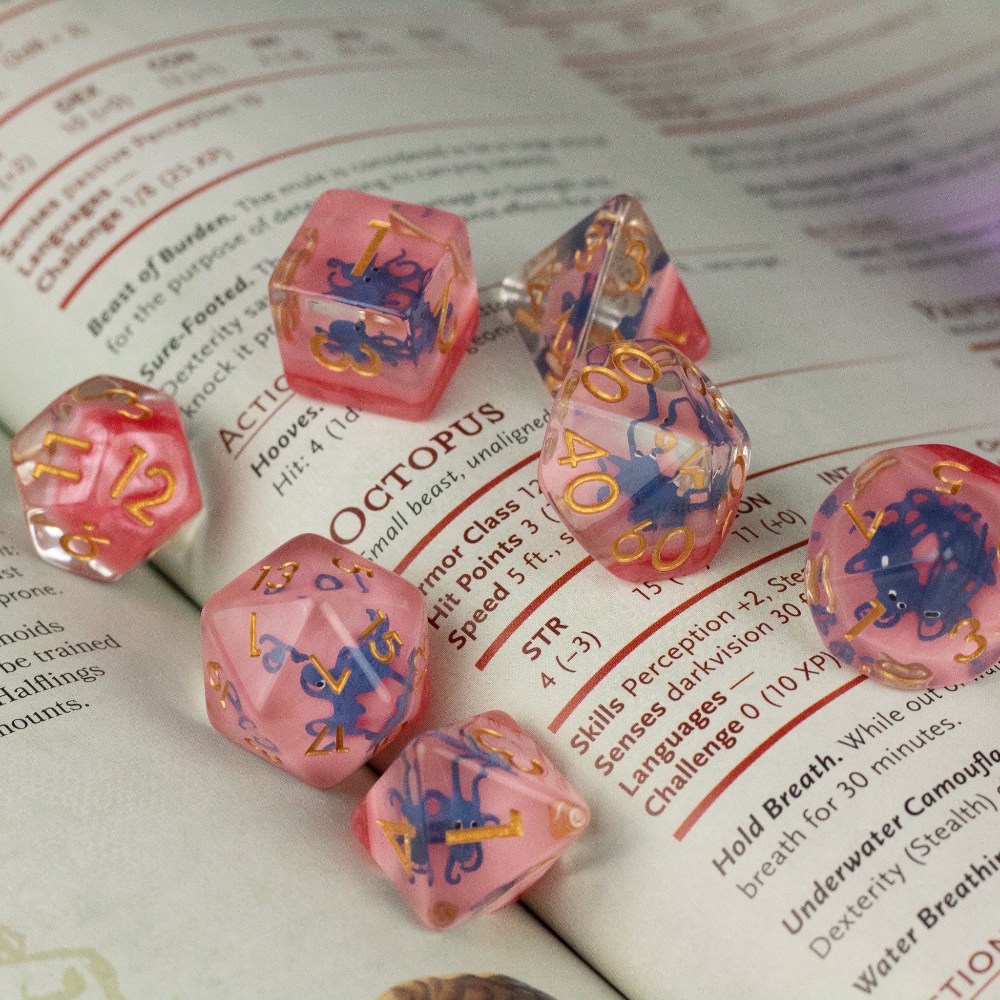 Dark Blue Octopus Dice Set - Translucent pink polyhedral dice set with dark blue octopus designs and gold numbering.